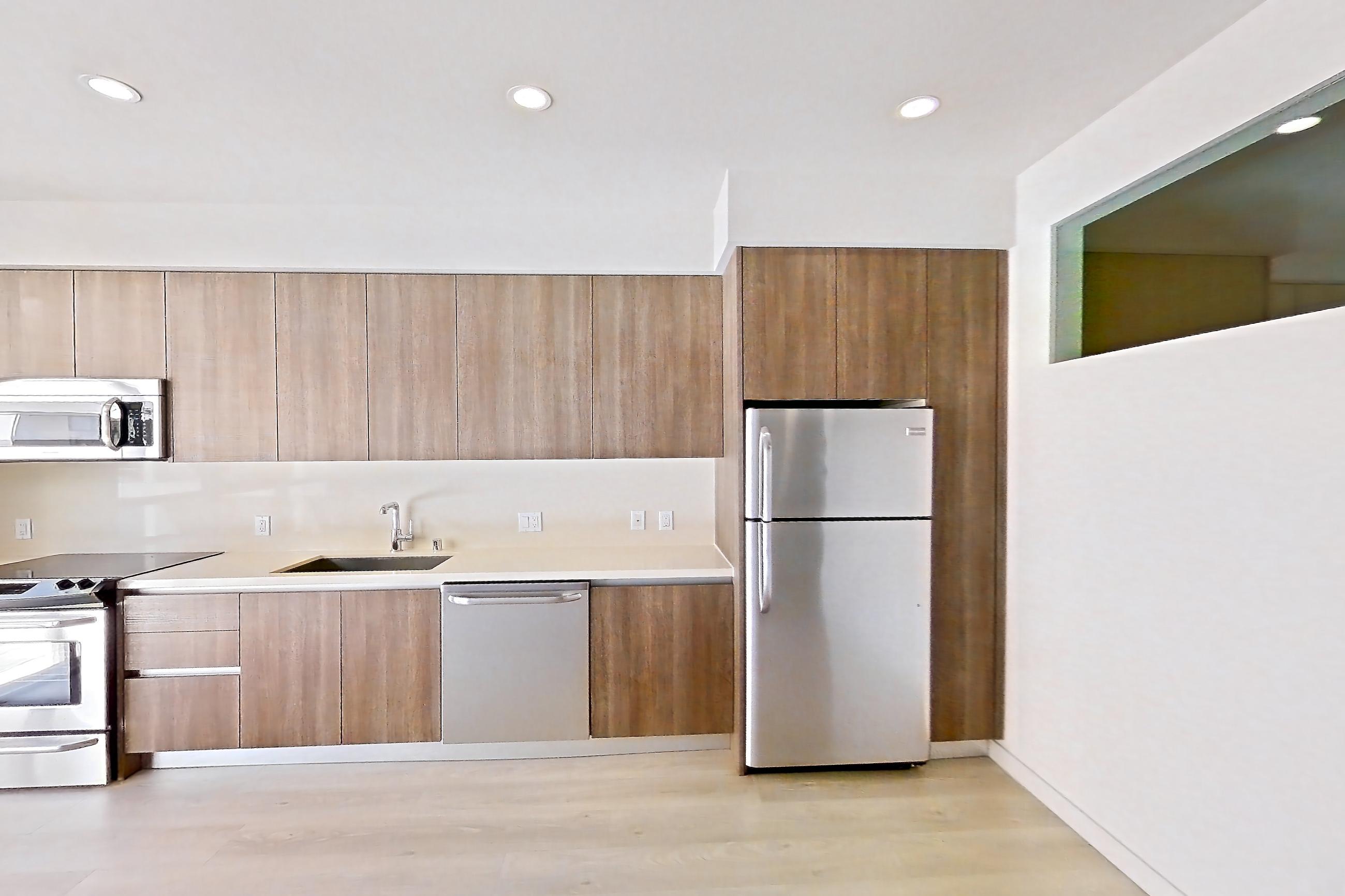 Living room with light countertops, light wood-finish flooring, and refrigerator, Apartment 0-5059 at Eighth and Grand