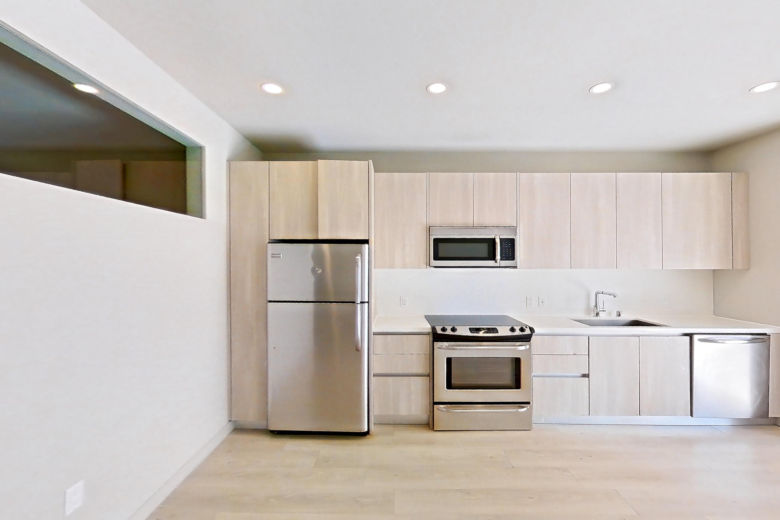 Living room with electric range, light countertops, light wood-finish flooring, oven/range, refrigerator, and stainless steel appliances, Apartment 0-5125 at Eighth and Grand
