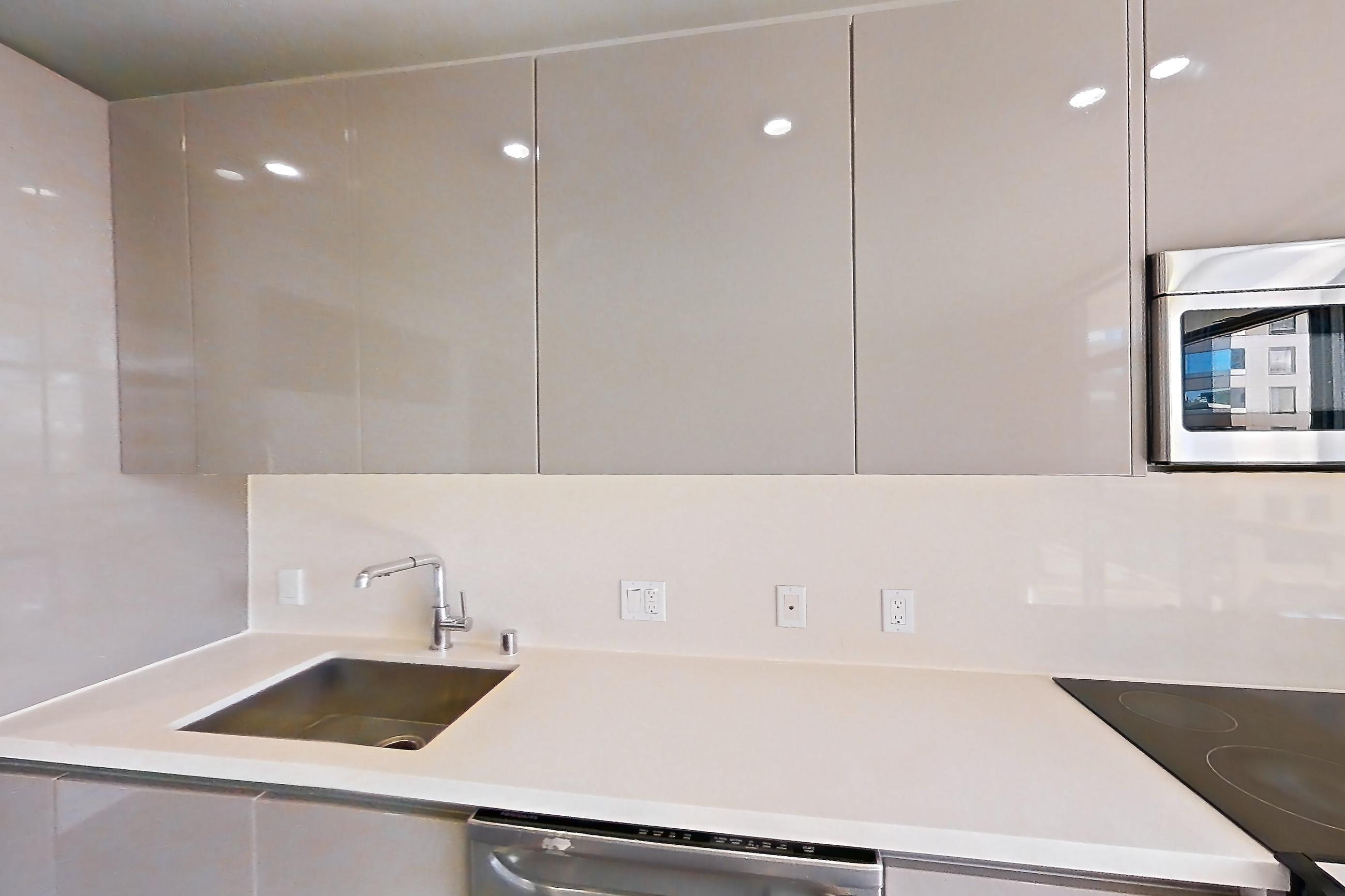 Kitchen with dark wood-finish flooring, dishwasher, light countertops, light wood-finish flooring, and stainless steel appliances, Apartment 0-5169 at Eighth and Grand
