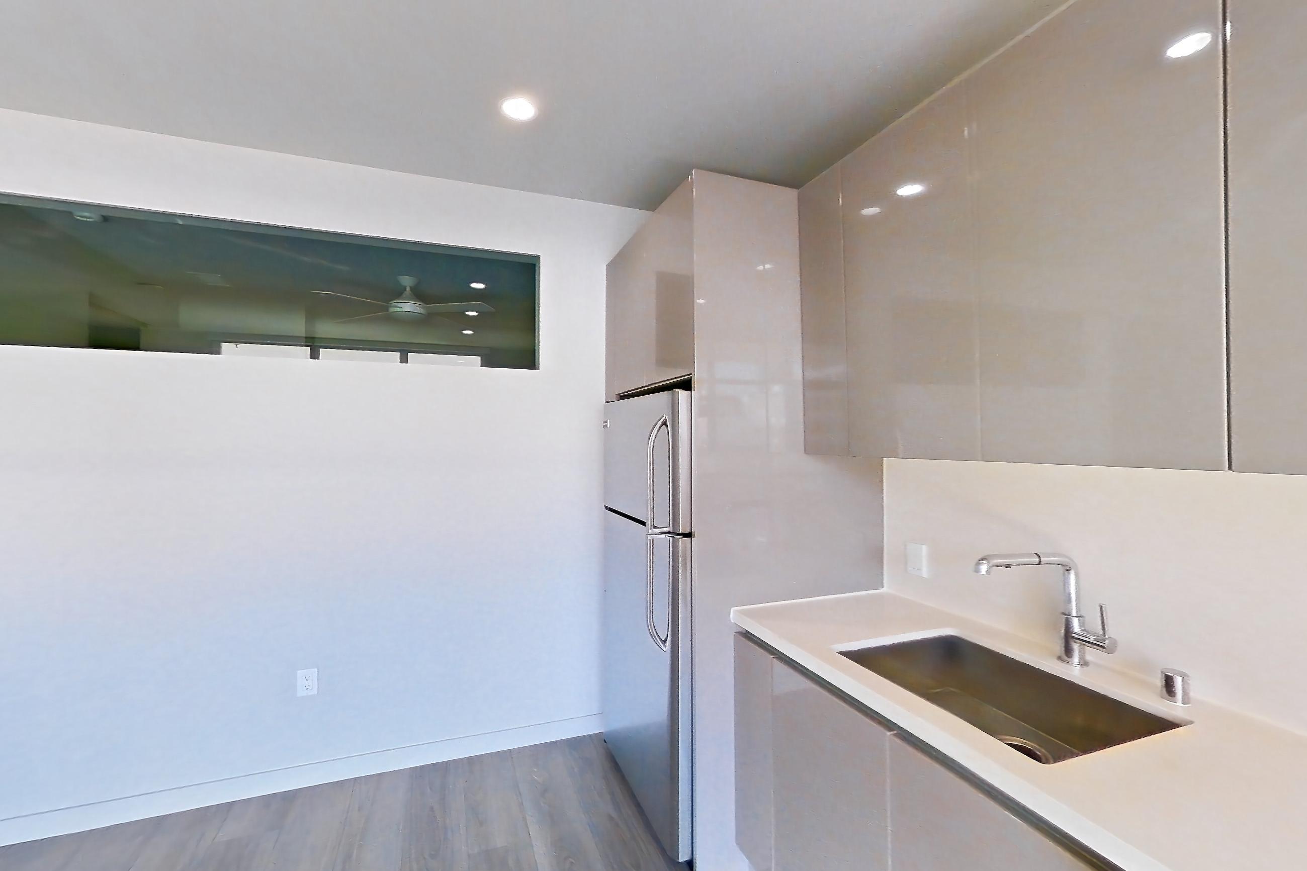 Kitchen with dark wood-finish flooring, dishwasher, light countertops, light wood-finish flooring, and stainless steel appliances, Apartment 0-5169 at Eighth and Grand