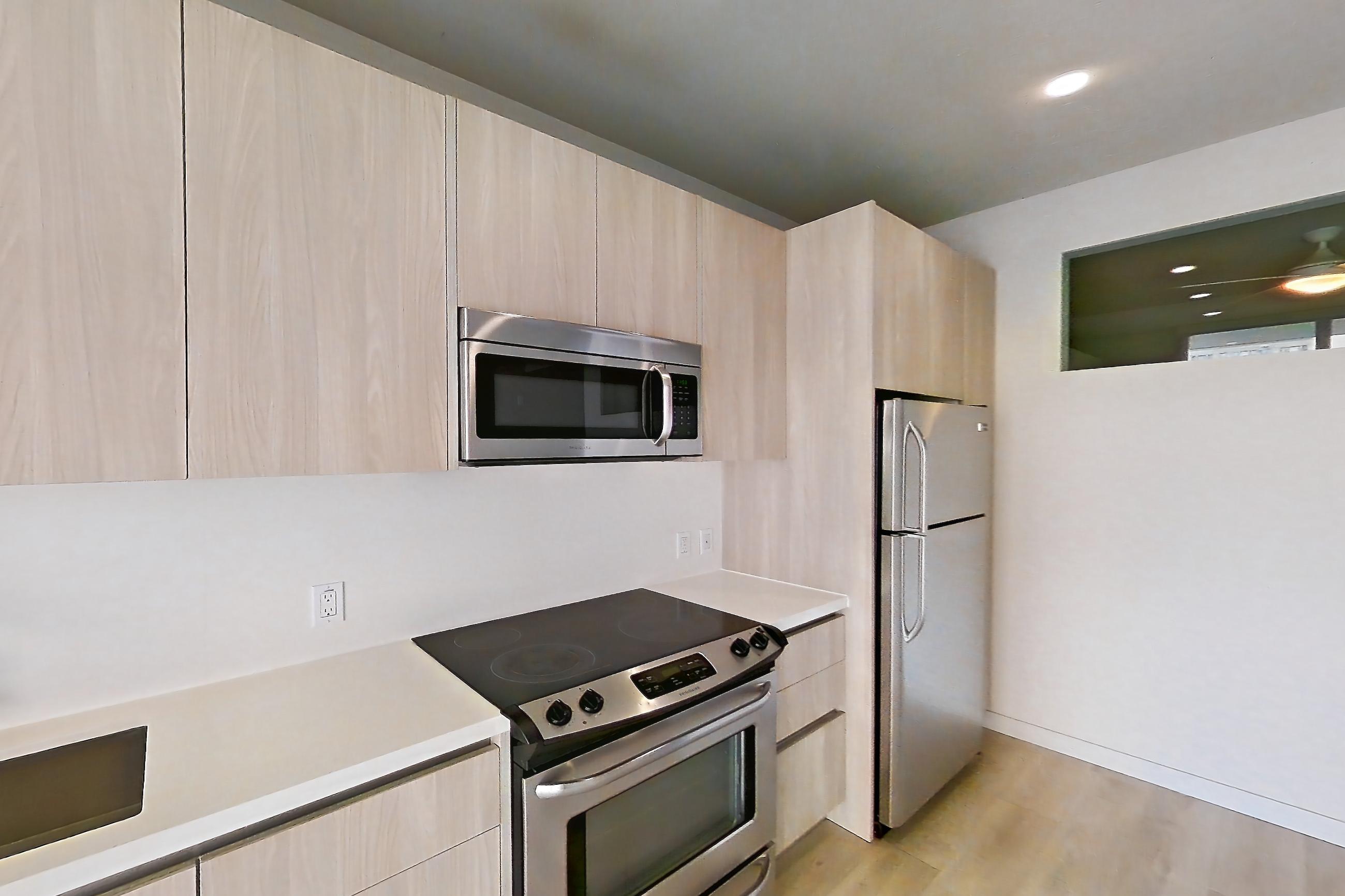 Kitchen with electric range, light countertops, light wood-finish flooring, microwave, oven/range, refrigerator, stainless steel appliances, and white appliances, Apartment 0-6137 at Eighth and Grand