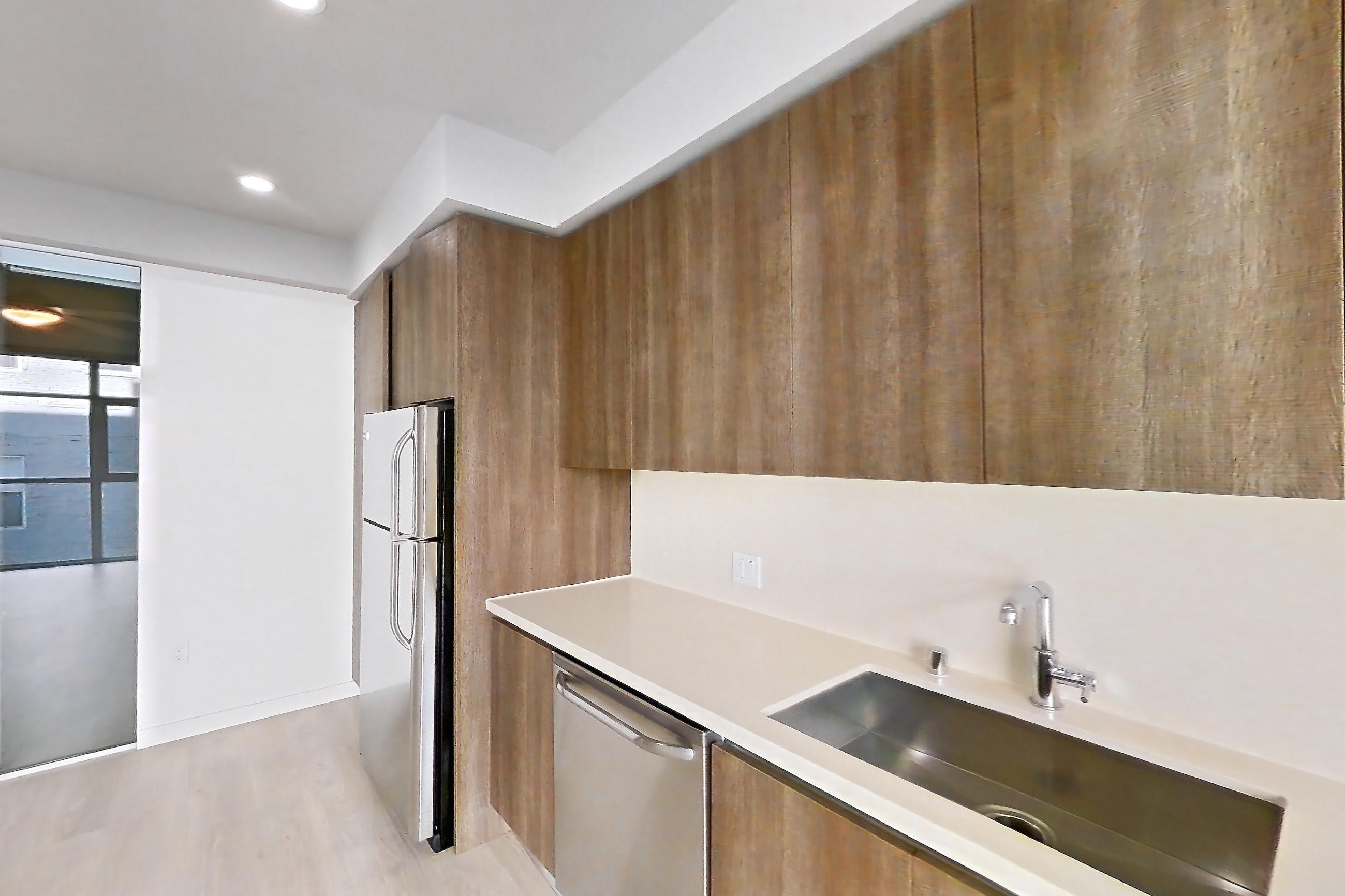 Kitchen with dishwasher, light countertops, light wood-finish flooring, and stainless steel appliances, Apartment 0-3071 at Eighth and Grand