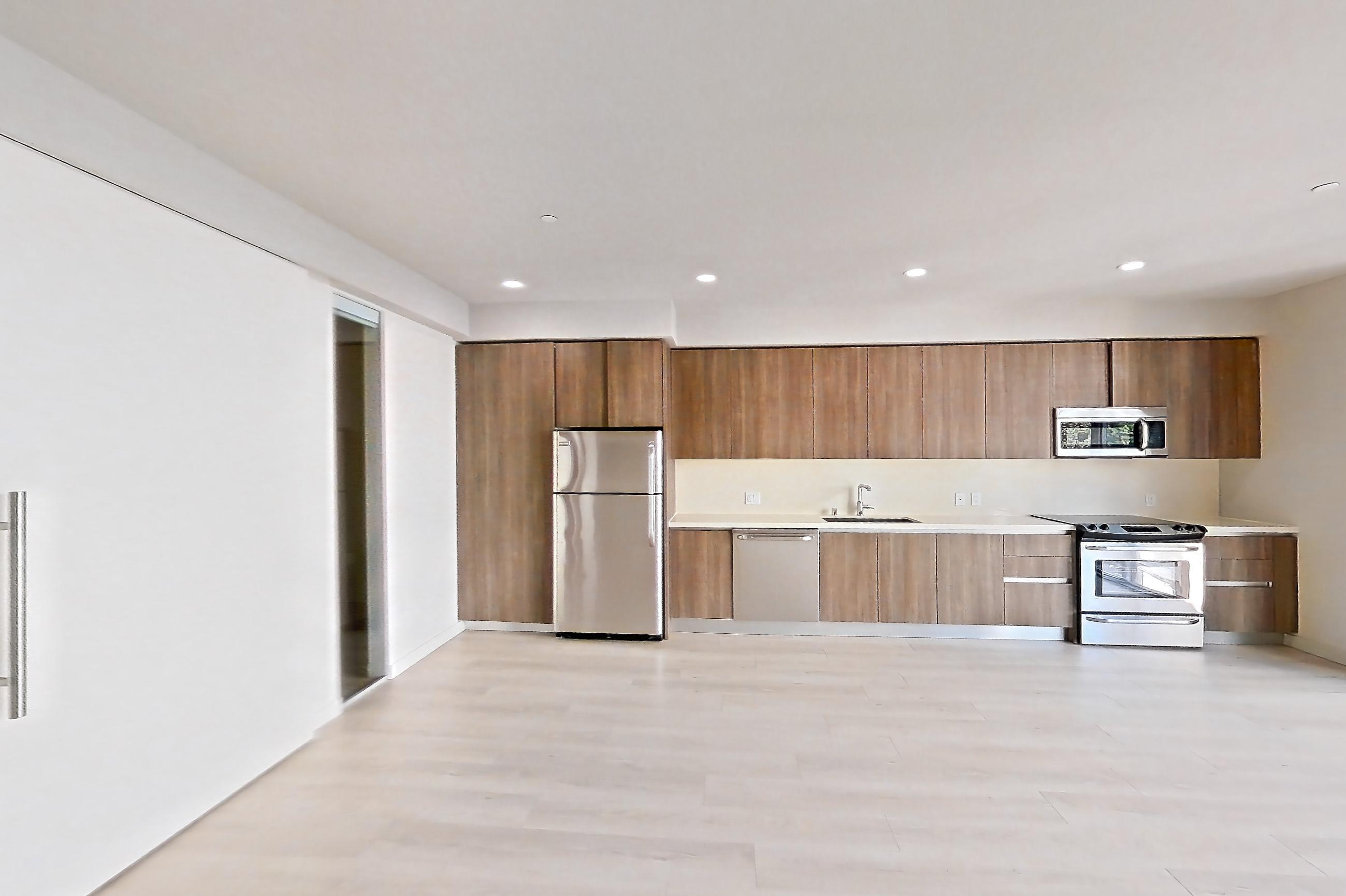 Living room with light wood-finish flooring, refrigerator, and stainless steel appliances, Apartment 0-3071 at Eighth and Grand
