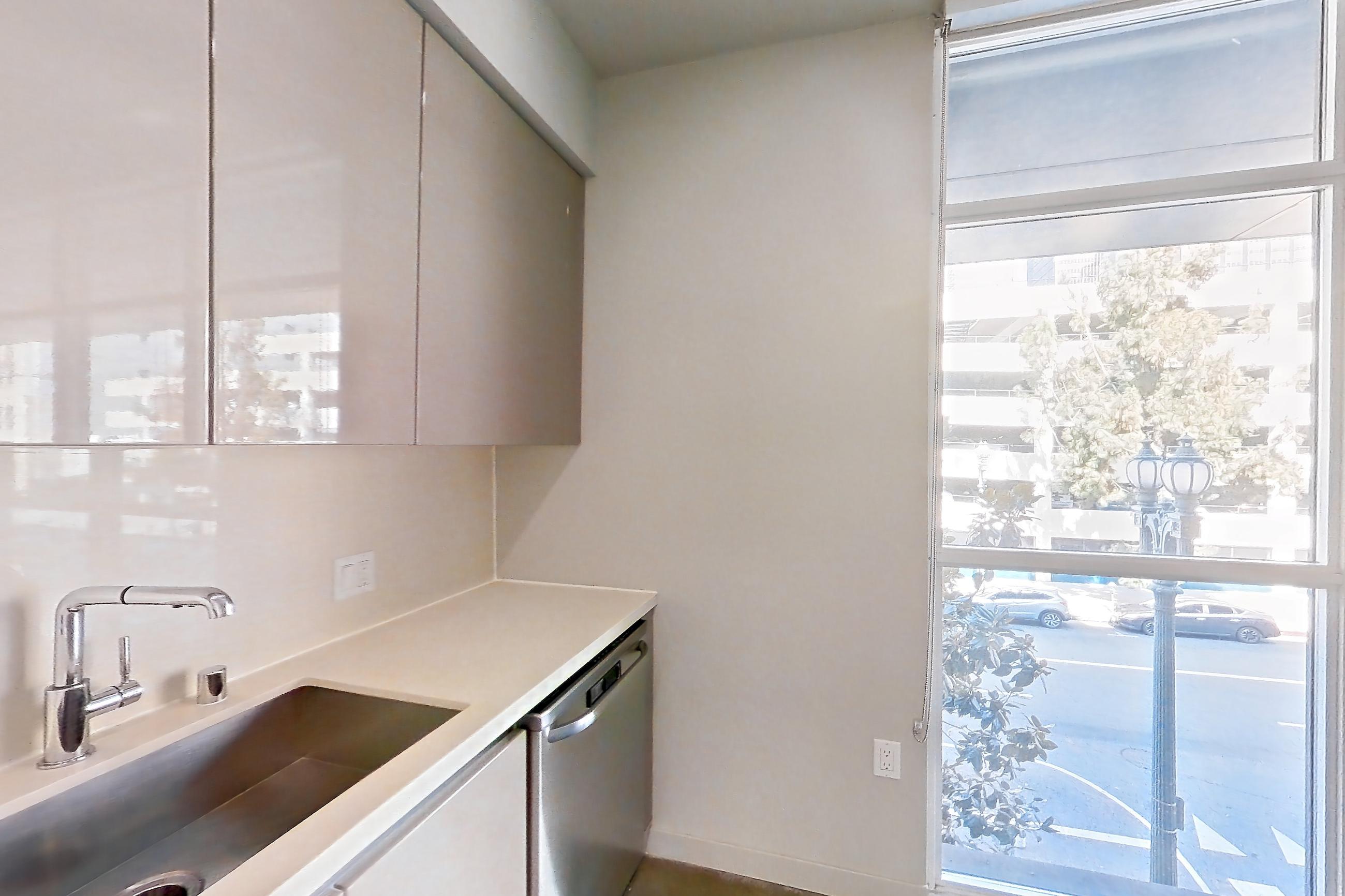 Kitchen with dishwasher, light countertops, polished concrete flooring, and stainless steel appliances, Apartment 0-2017 at Eighth and Grand