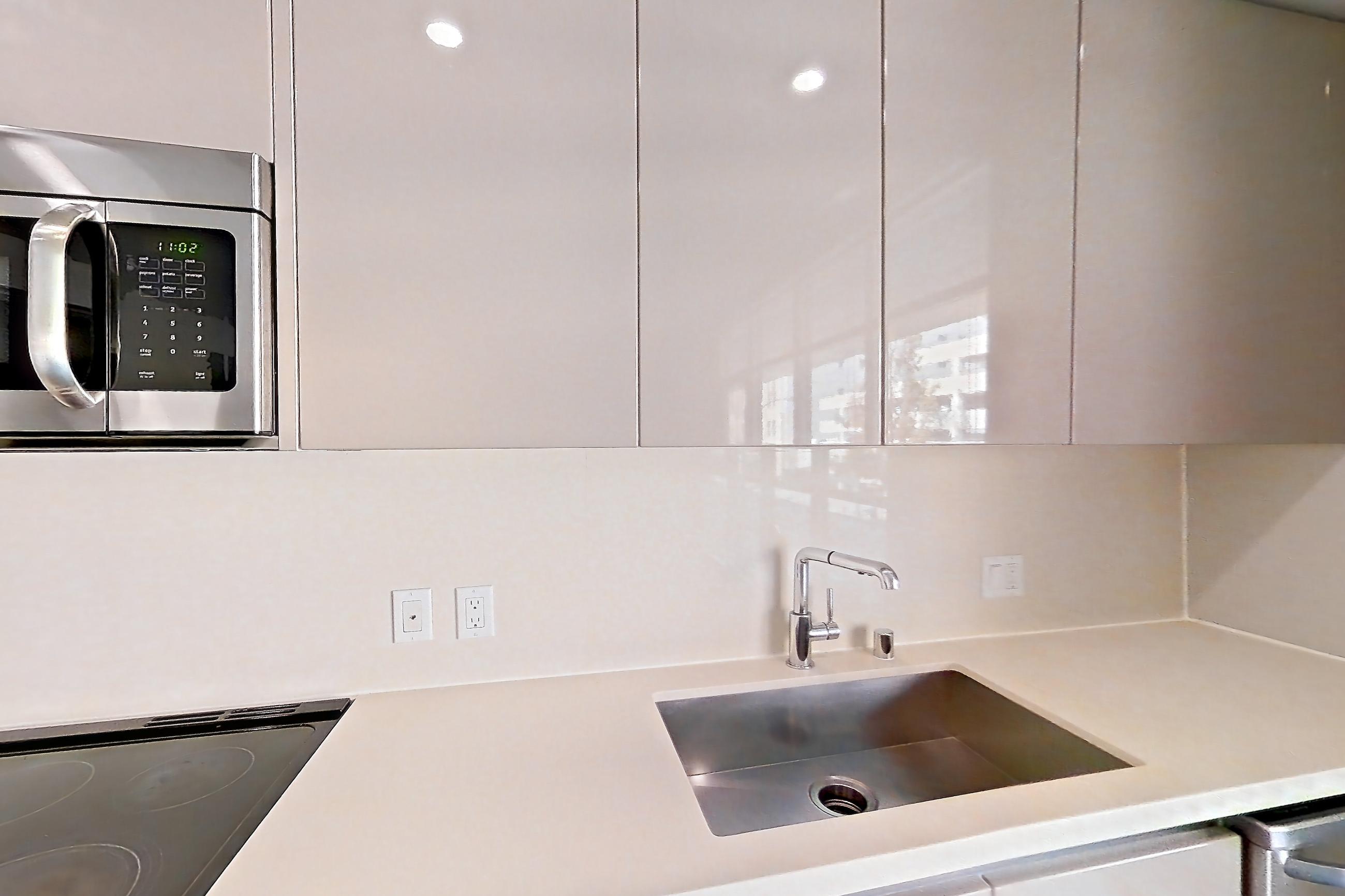 Kitchen with dishwasher, light countertops, polished concrete flooring, and stainless steel appliances, Apartment 0-2017 at Eighth and Grand