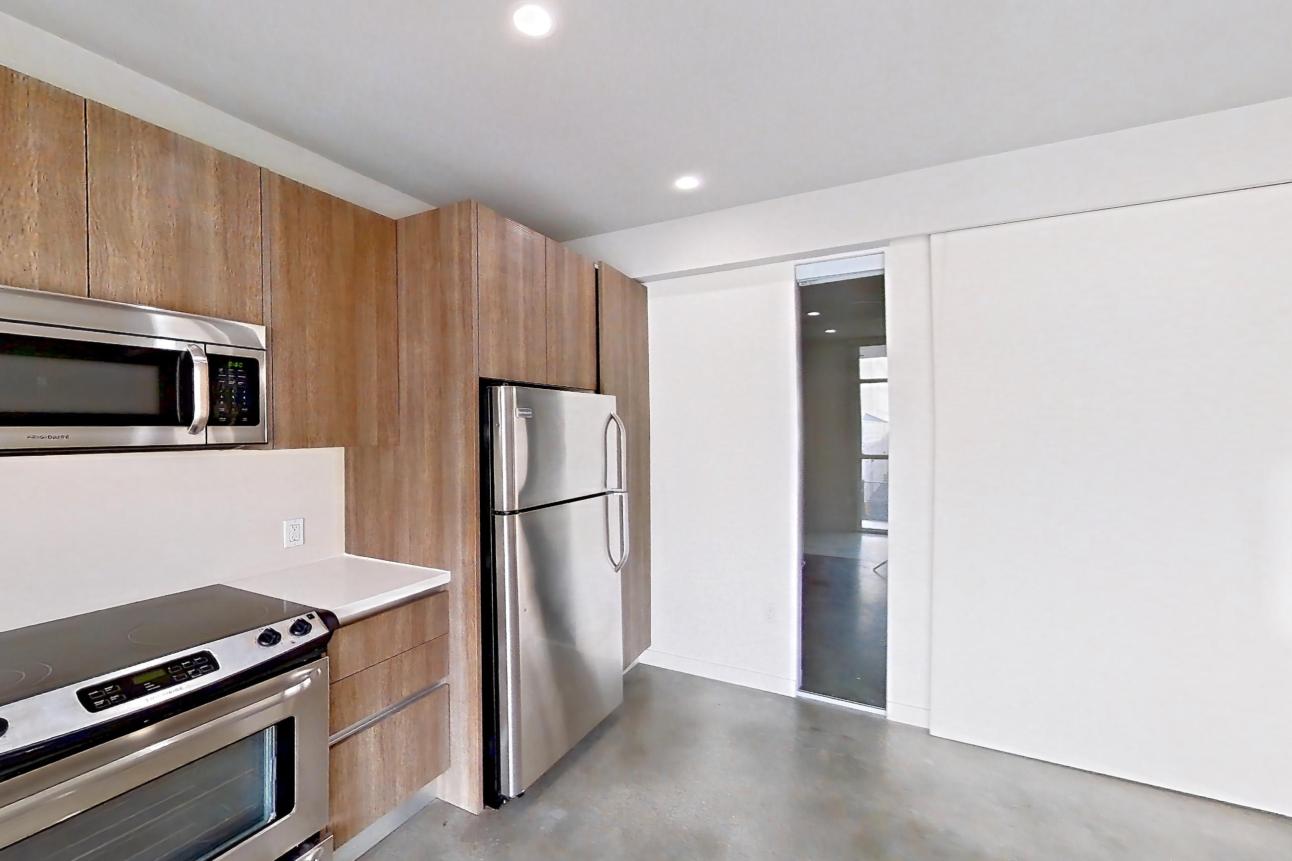 Kitchen with dark concrete flooring, light concrete flooring, polished concrete flooring, refrigerator, and stainless steel appliances, Apartment 0-2037 at Eighth and Grand