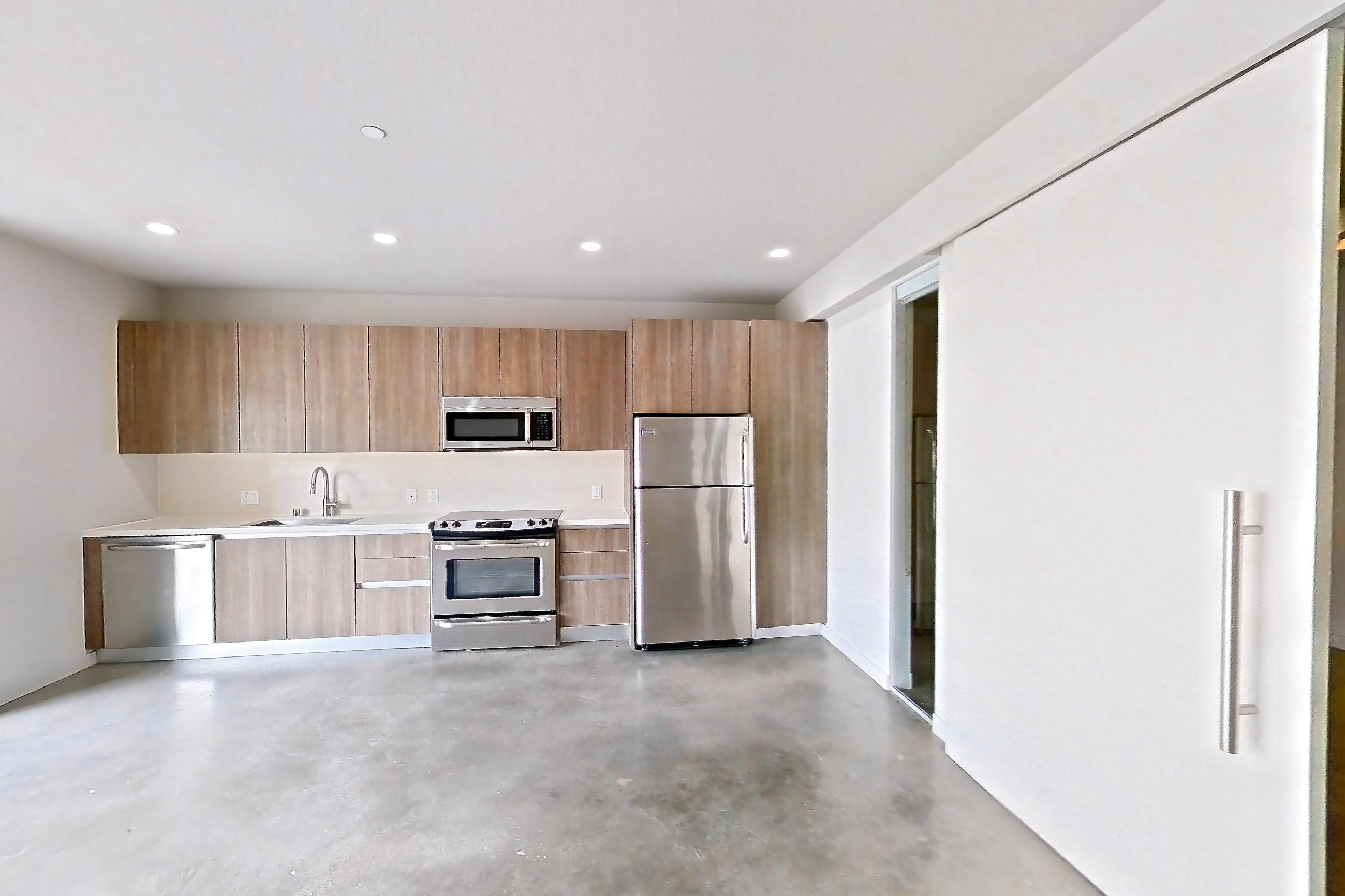 Living room with light countertops, oven/range, polished concrete flooring, refrigerator, and stainless steel appliances, Apartment 0-2037 at Eighth and Grand