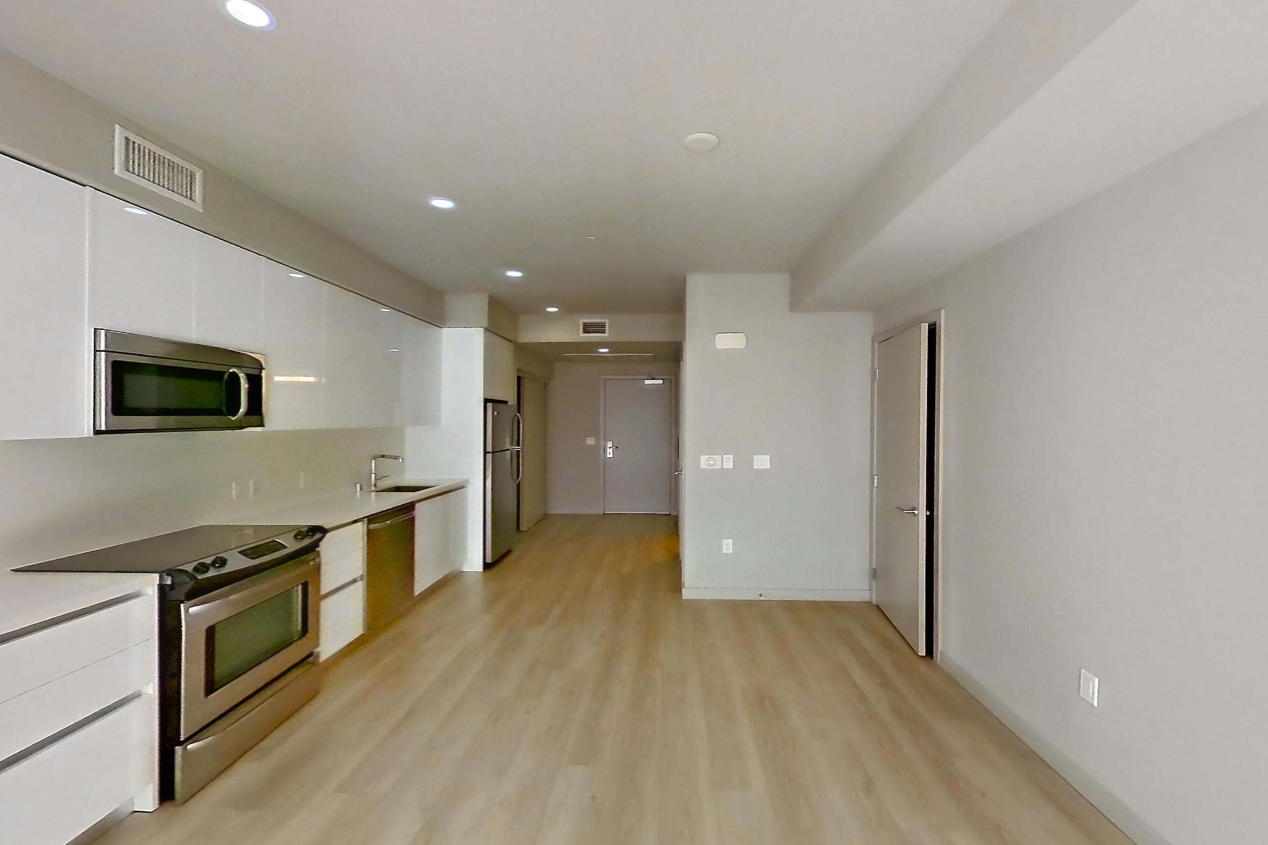 Living space with dishwasher, electric range, light countertops, light wood-finish flooring, microwave, oven/range, refrigerator, and stainless steel appliances, Apartment 0-3089 at Eighth and Grand