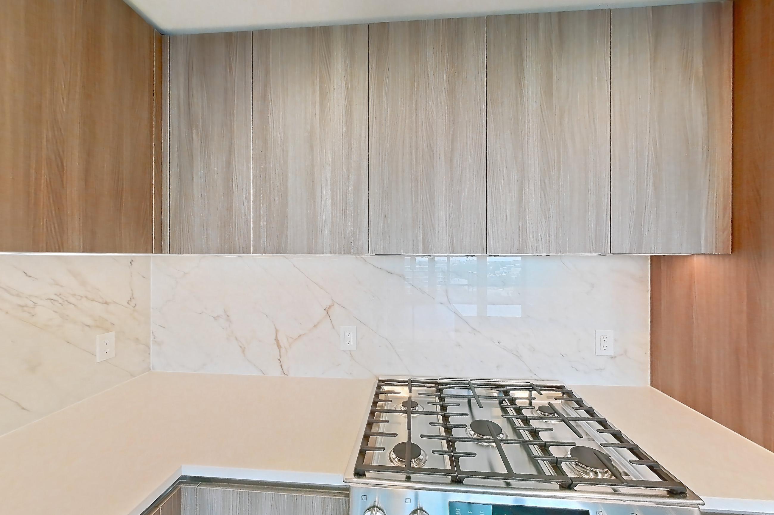 Kitchen with gas range, light stone countertops, light wood-finish flooring, oven/range, and stainless steel appliances, Apartment 0619 at Aerie