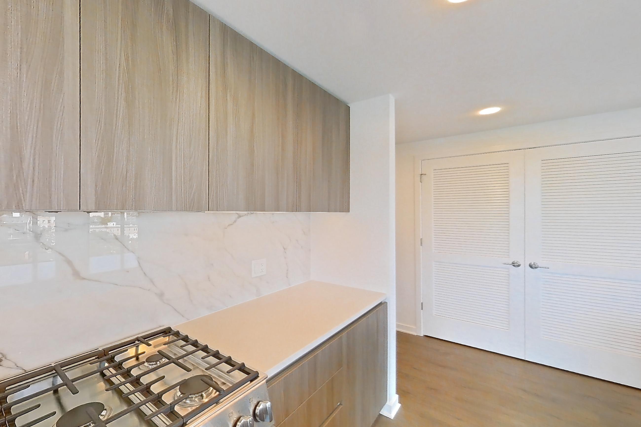 Kitchen with dark wood-finish flooring, gas range, light stone countertops, light wood-finish flooring, oven/range, and stainless steel appliances, Apartment 0721 at Aerie