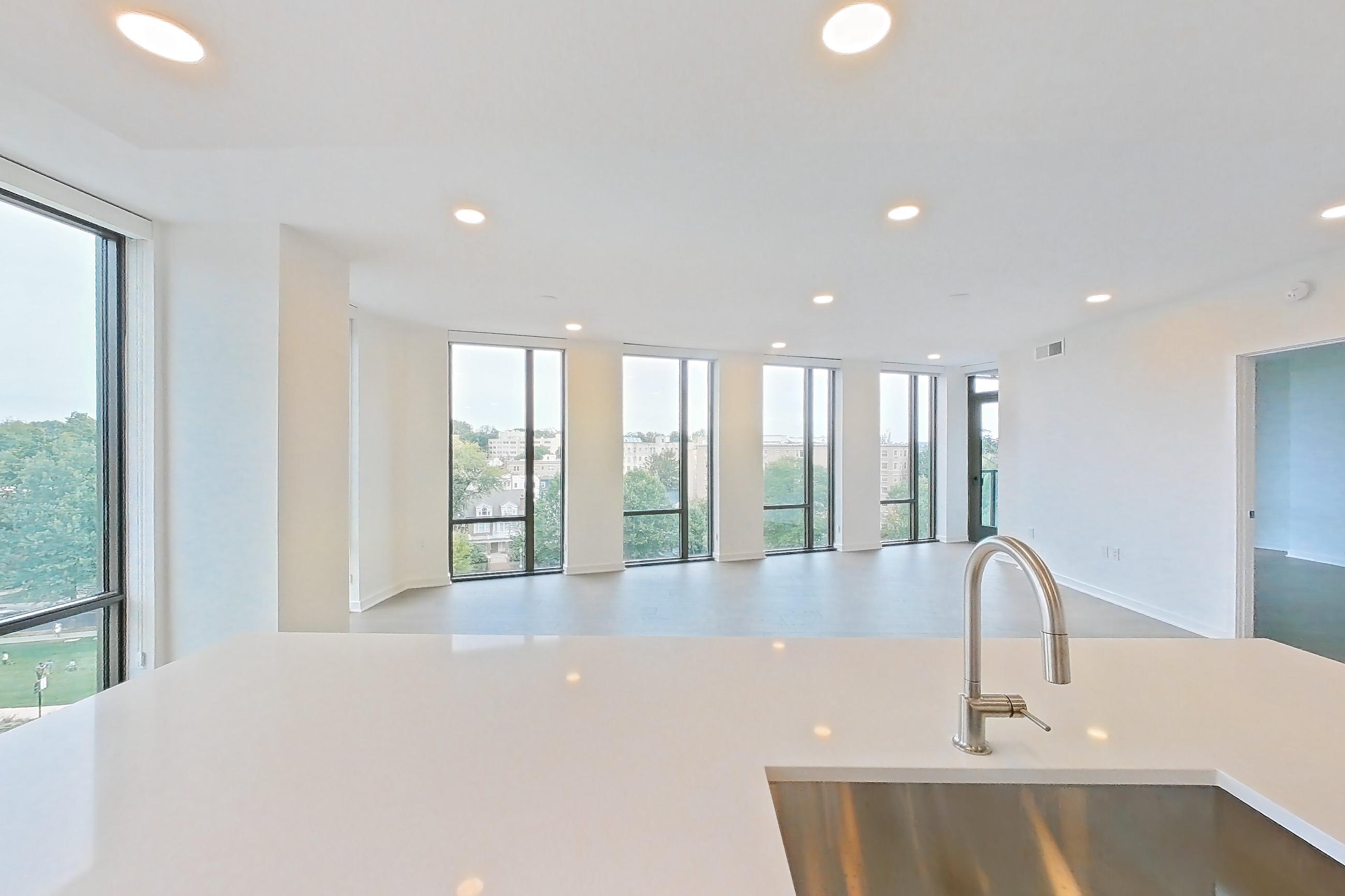 Kitchen with black appliances, cooktop, electric cooktop, gas range, light stone countertops, light tile flooring, light wood-finish flooring, oven/range, and stainless steel appliances, Apartment 0622 at Aerie