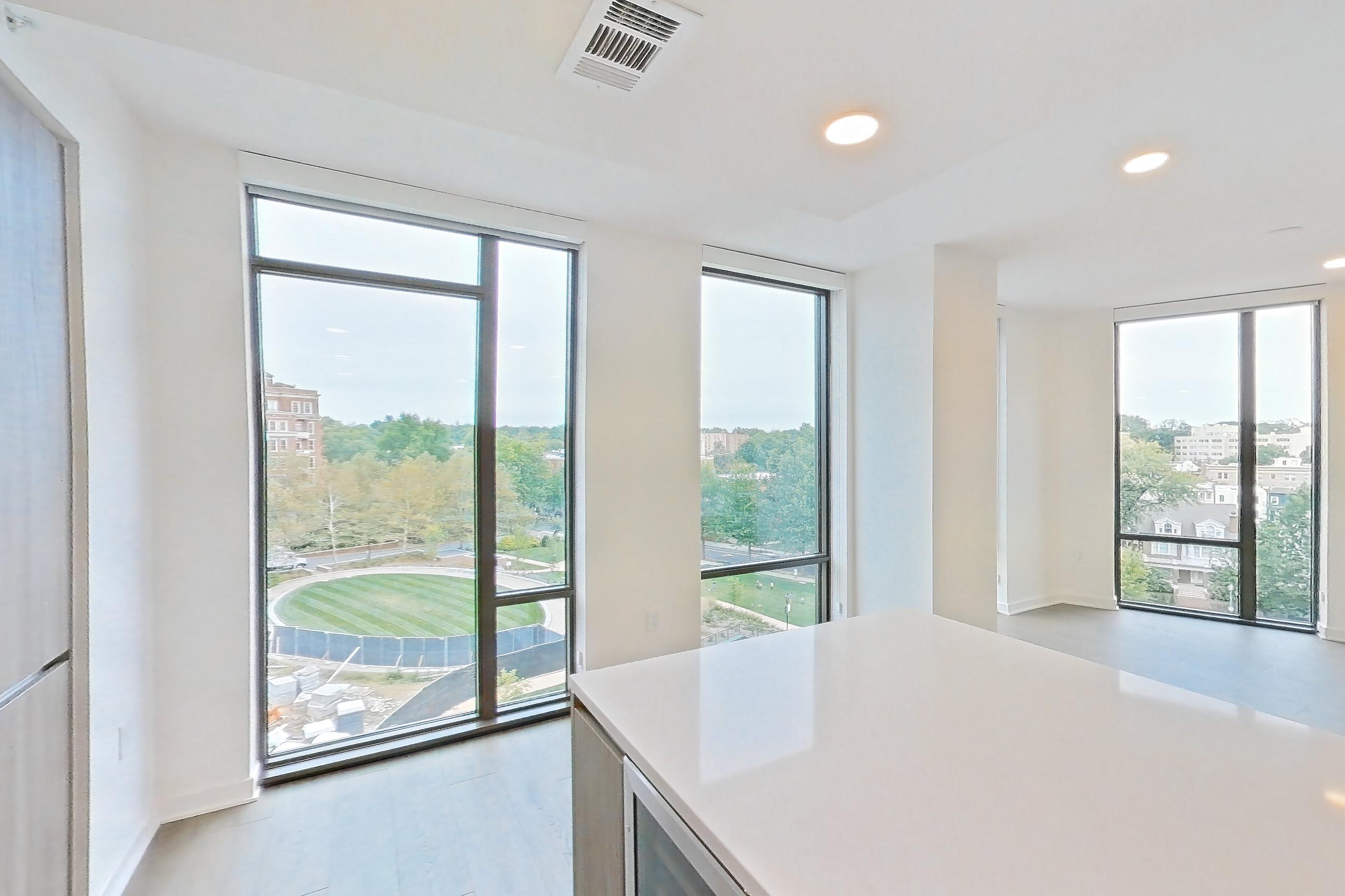 Kitchen with black appliances, cooktop, electric cooktop, gas range, light stone countertops, light tile flooring, light wood-finish flooring, oven/range, and stainless steel appliances, Apartment 0622 at Aerie
