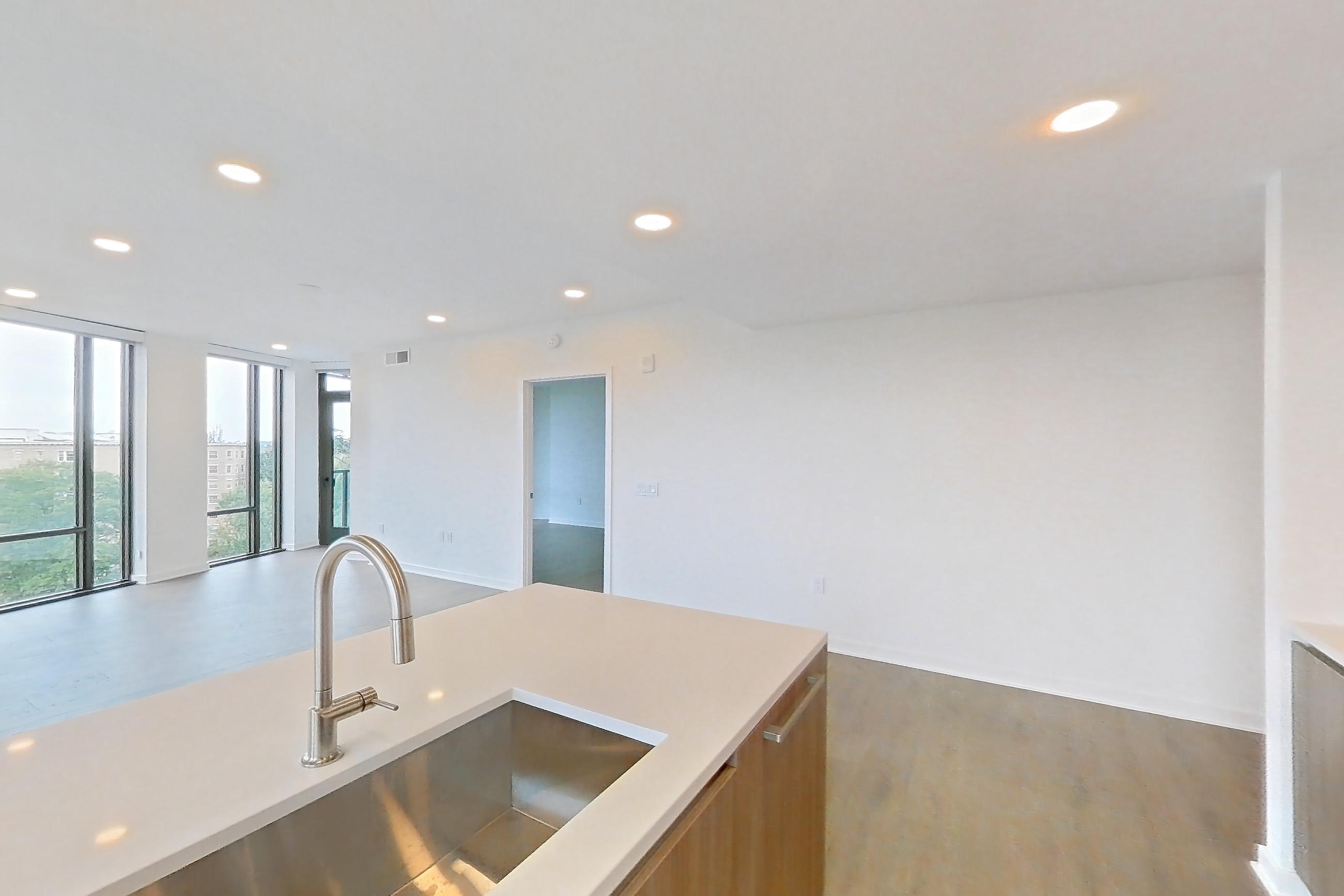 Kitchen with black appliances, cooktop, electric cooktop, gas range, light stone countertops, light tile flooring, light wood-finish flooring, oven/range, and stainless steel appliances, Apartment 0622 at Aerie