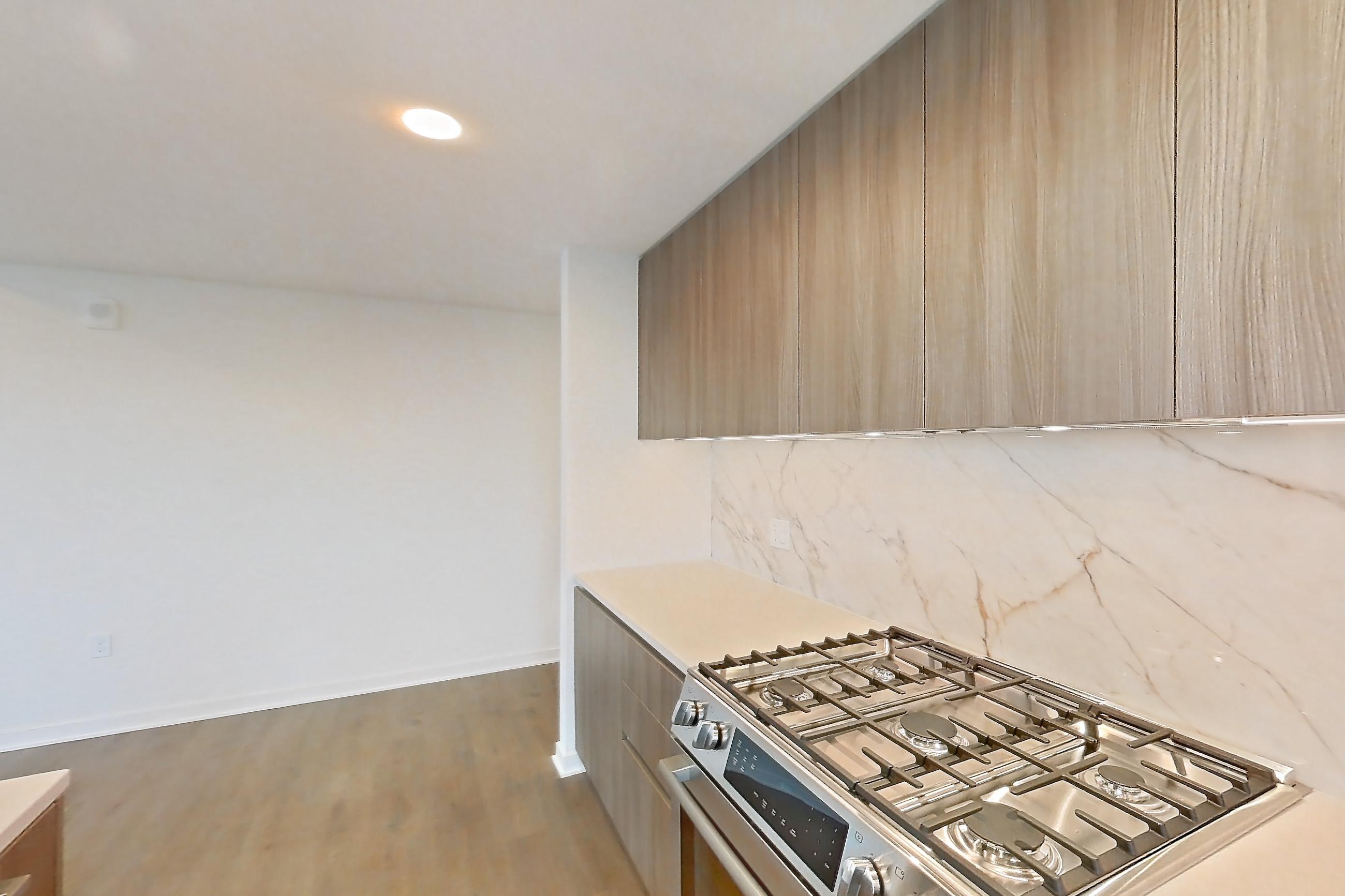 Kitchen with gas range, light stone countertops, light tile flooring, light wood-finish flooring, oven/range, and stainless steel appliances, Apartment 0822 at Aerie