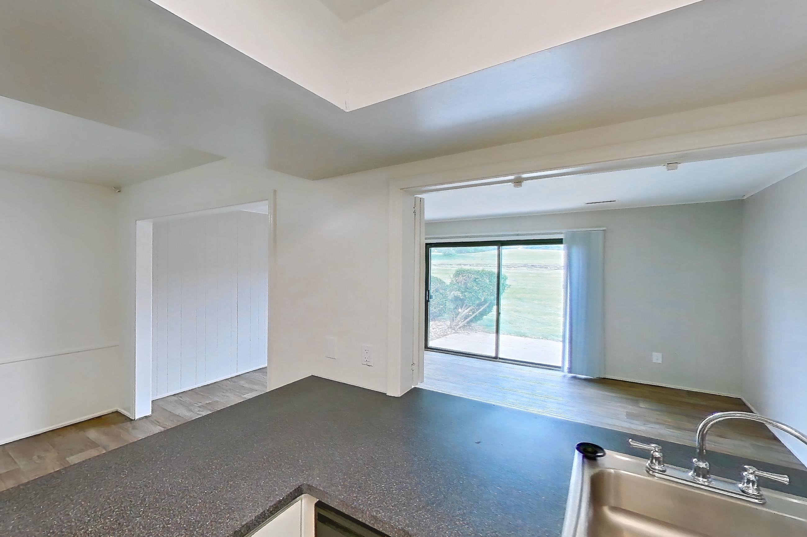 Kitchen with black appliances, dark countertops, dark stone countertops, dishwasher, electric range, light wood-finish flooring, oven/range, refrigerator, and white appliances, Apartment 5242ST at Canterbury Green