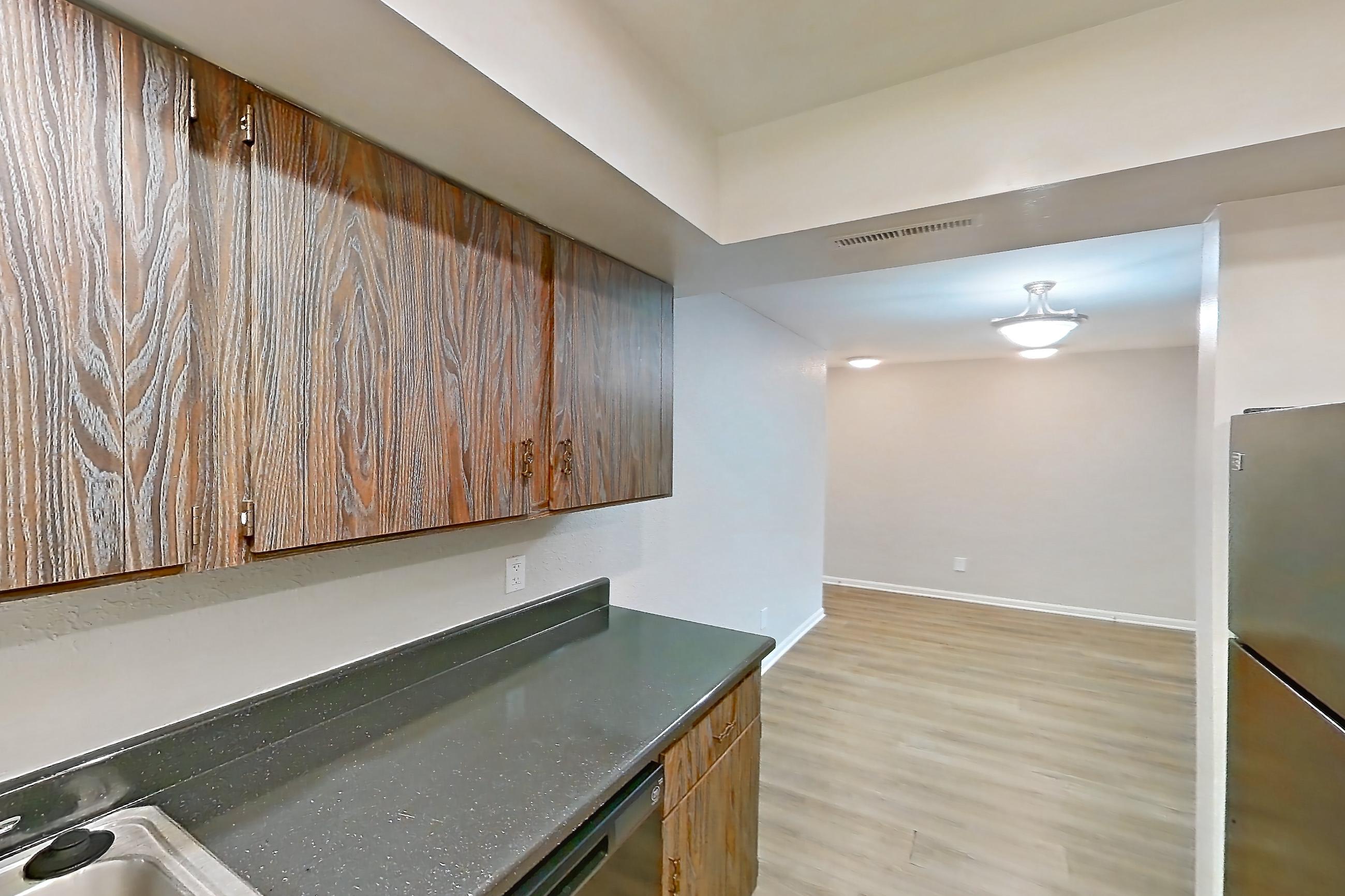 Kitchen with black appliances, dark countertops, electric range, light wood-finish flooring, oven/range, and refrigerator, Apartment 2611-7AB at Canterbury Green