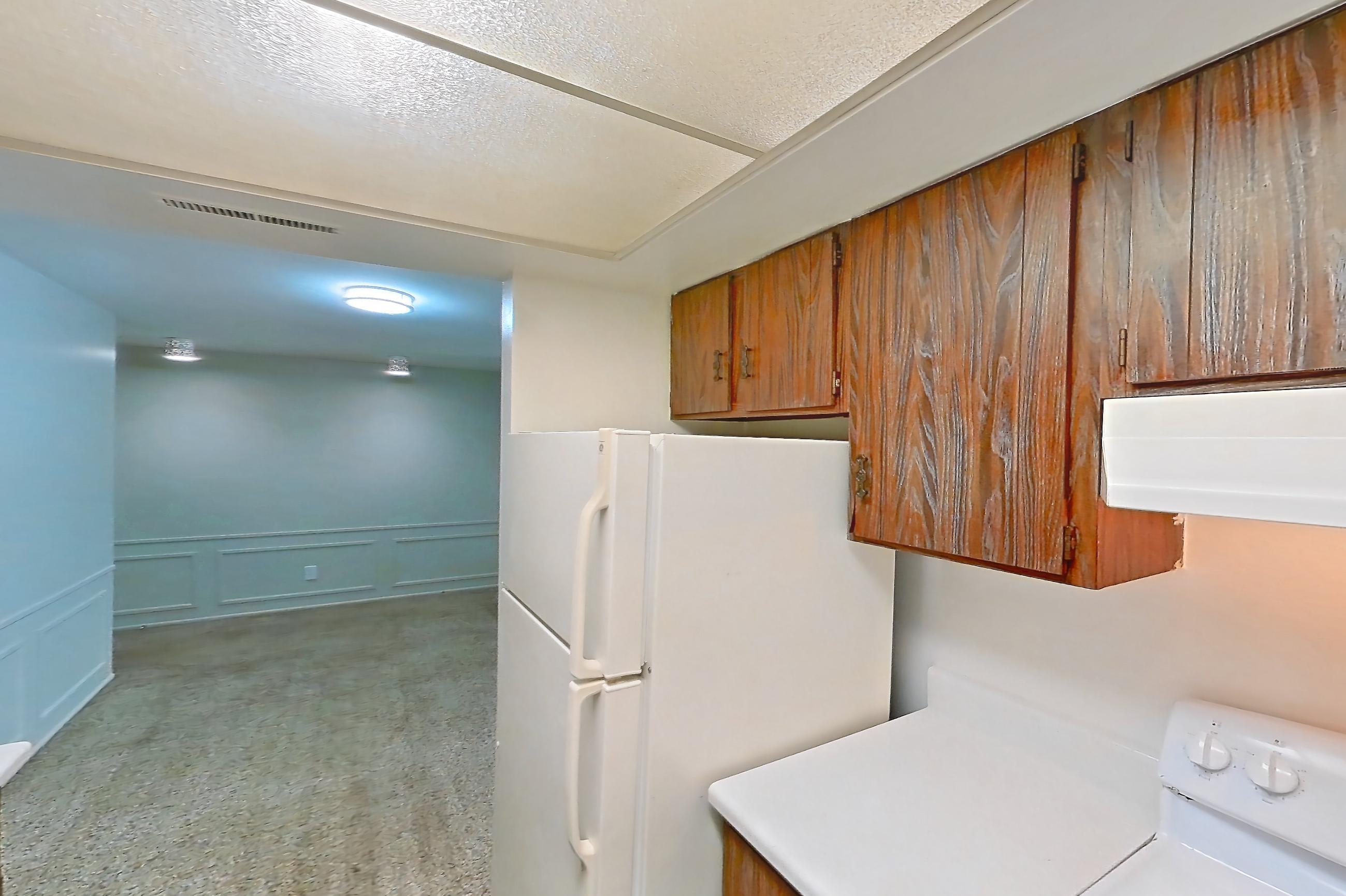 Kitchen with black appliances, dishwasher, electric range, light carpet, light countertops, light wood-finish flooring, oven/range, refrigerator, and white appliances, Apartment 2603-7AB at Canterbury Green