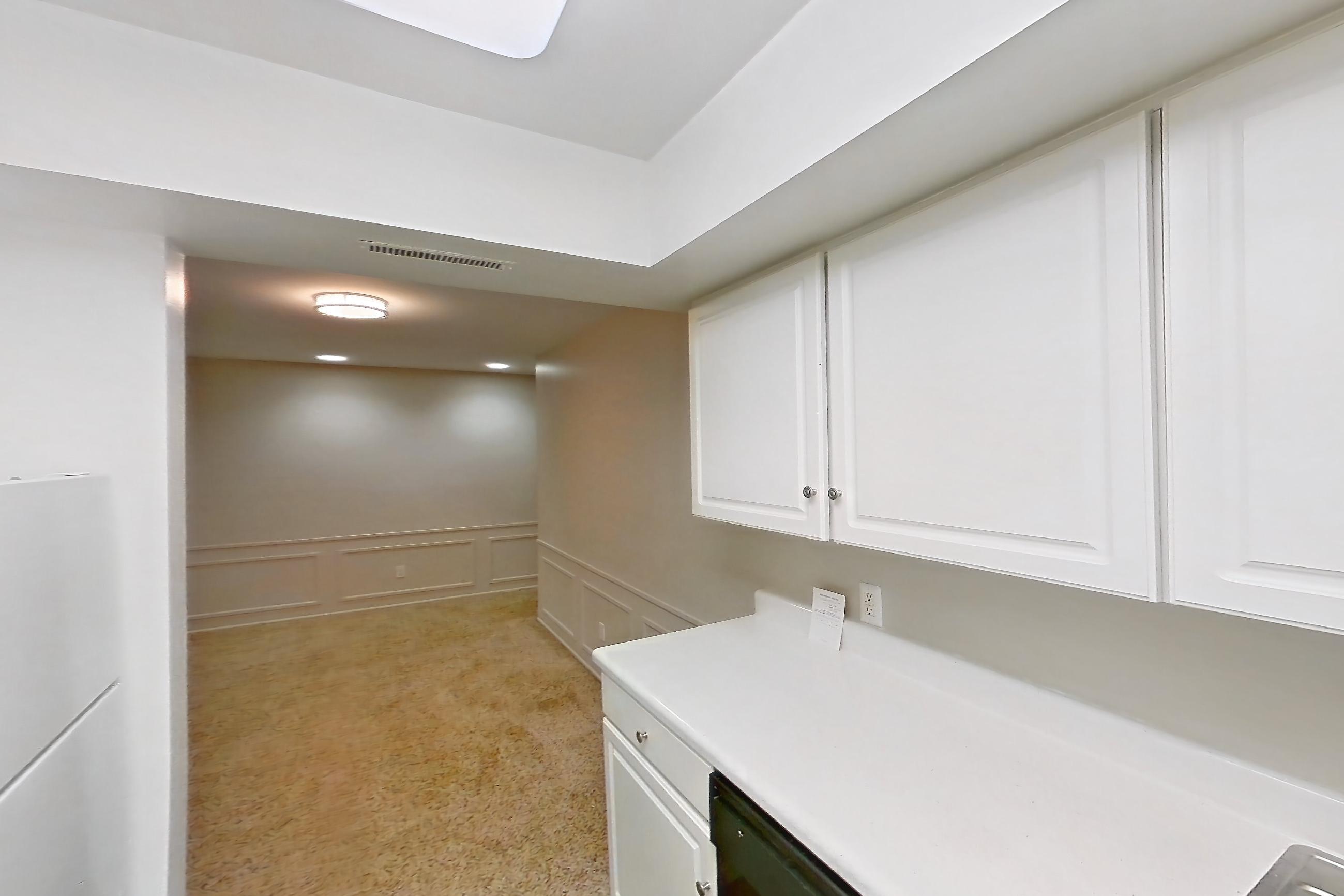 Kitchen with black appliances, dishwasher, electric range, light carpet, light countertops, light wood-finish flooring, refrigerator, and white appliances, Apartment 512410ST at Canterbury Green