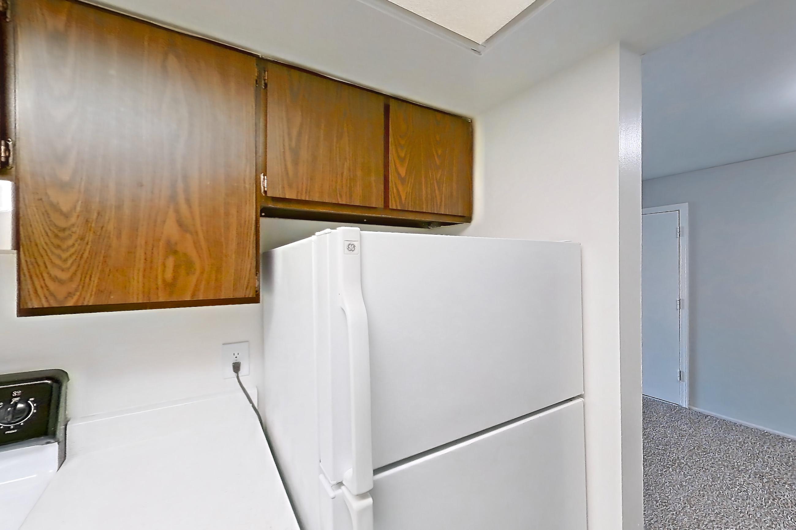 Kitchen with black appliances, dishwasher, light countertops, light stone countertops, light wood-finish flooring, oven/range, refrigerator, and white appliances, Apartment 2803-8NO at Canterbury Green