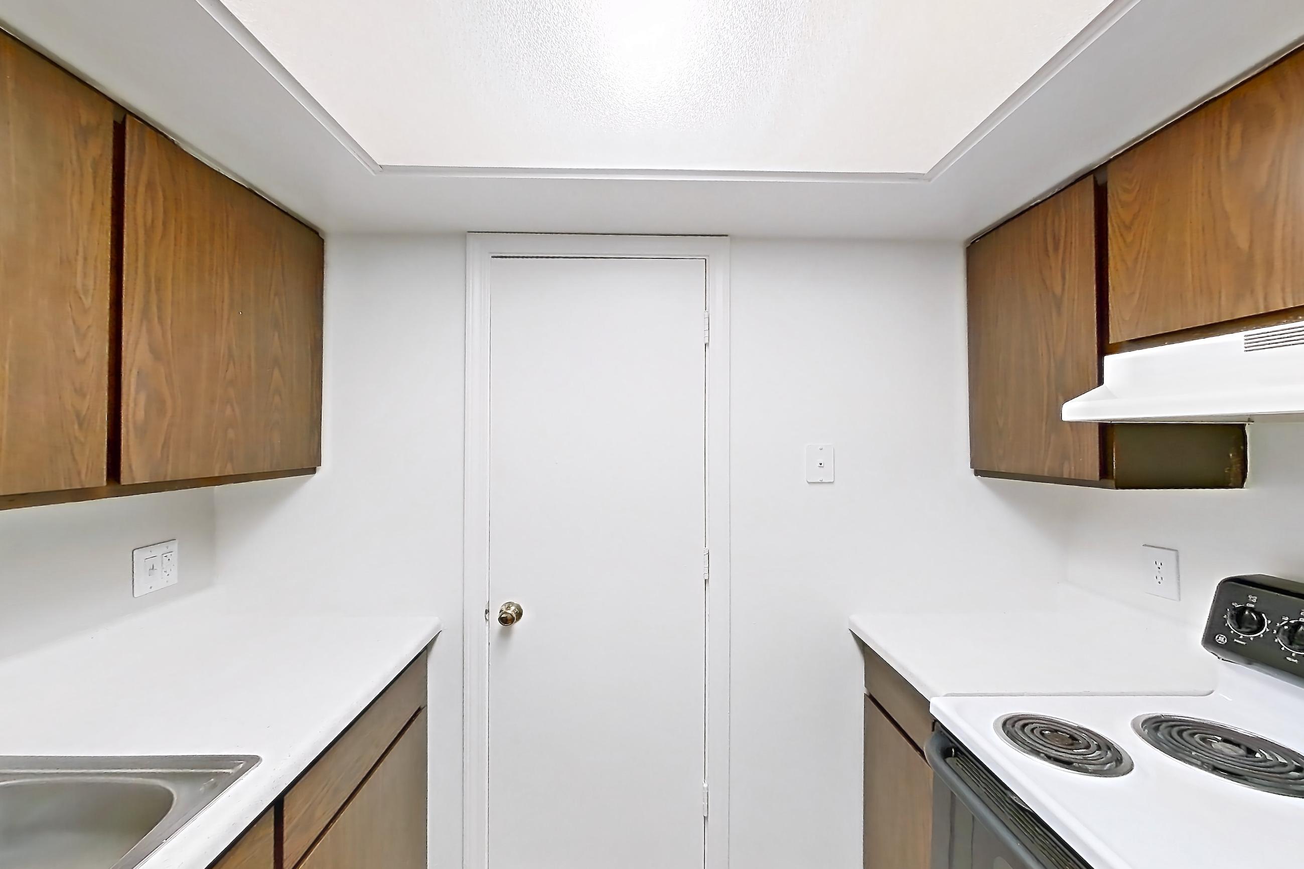 Kitchen with black appliances, dishwasher, light countertops, light stone countertops, light wood-finish flooring, oven/range, refrigerator, and white appliances, Apartment 2803-8NO at Canterbury Green
