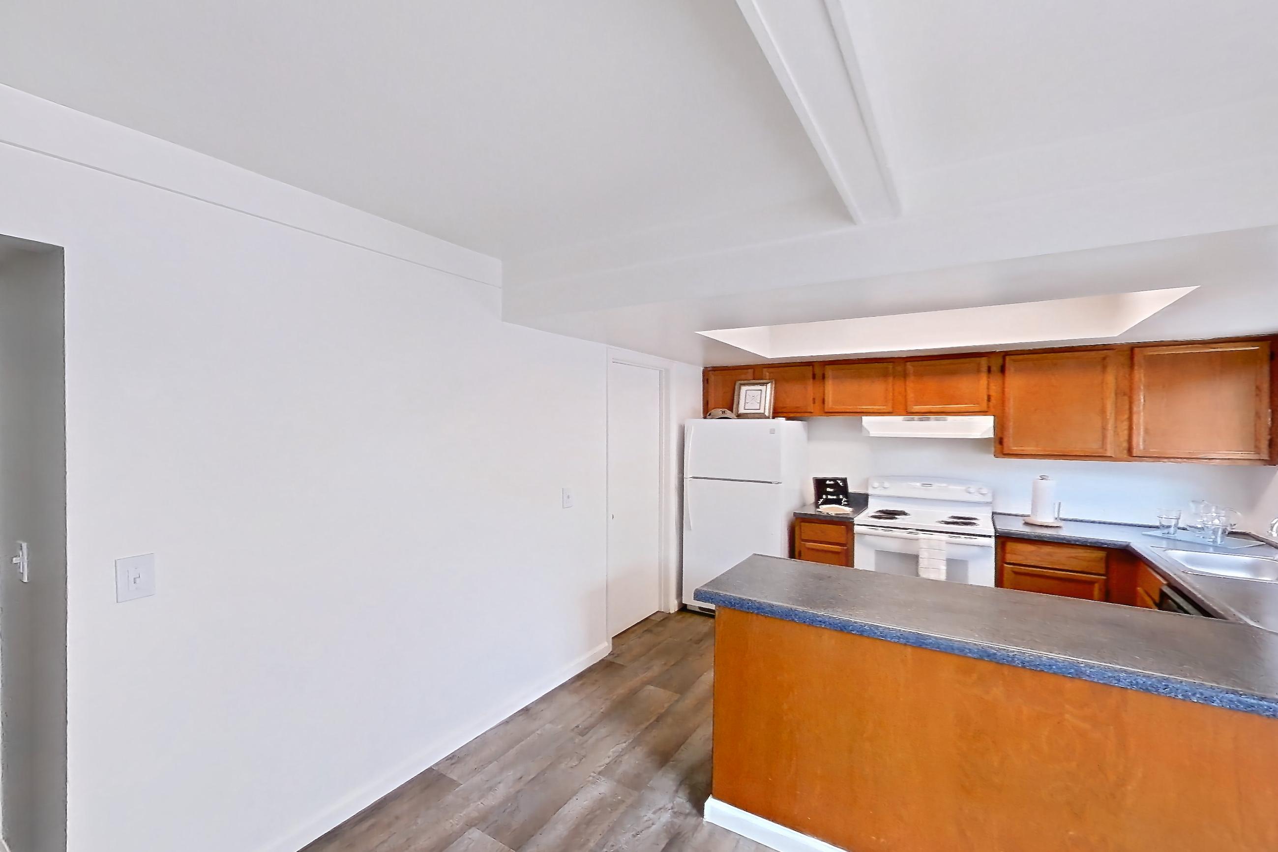 Dining room with dark countertops, dark wood-finish flooring, electric range, oven/range, refrigerator, and white appliances, Apartment 3014CA at Canterbury Green