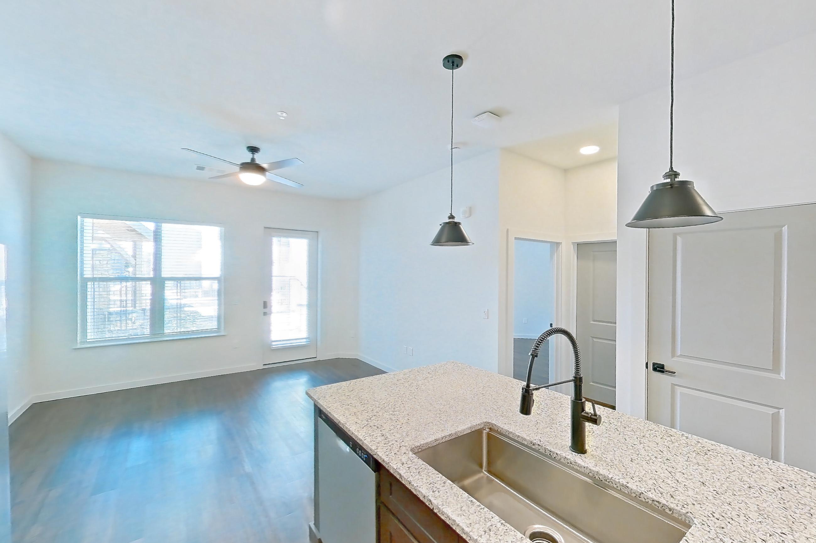 Kitchen with dark wood-finish flooring, electric range, light stone countertops, microwave, oven/range, refrigerator, stainless steel appliances, and water & ice dispenser, Apartment 1-121 at Cortland Peterson