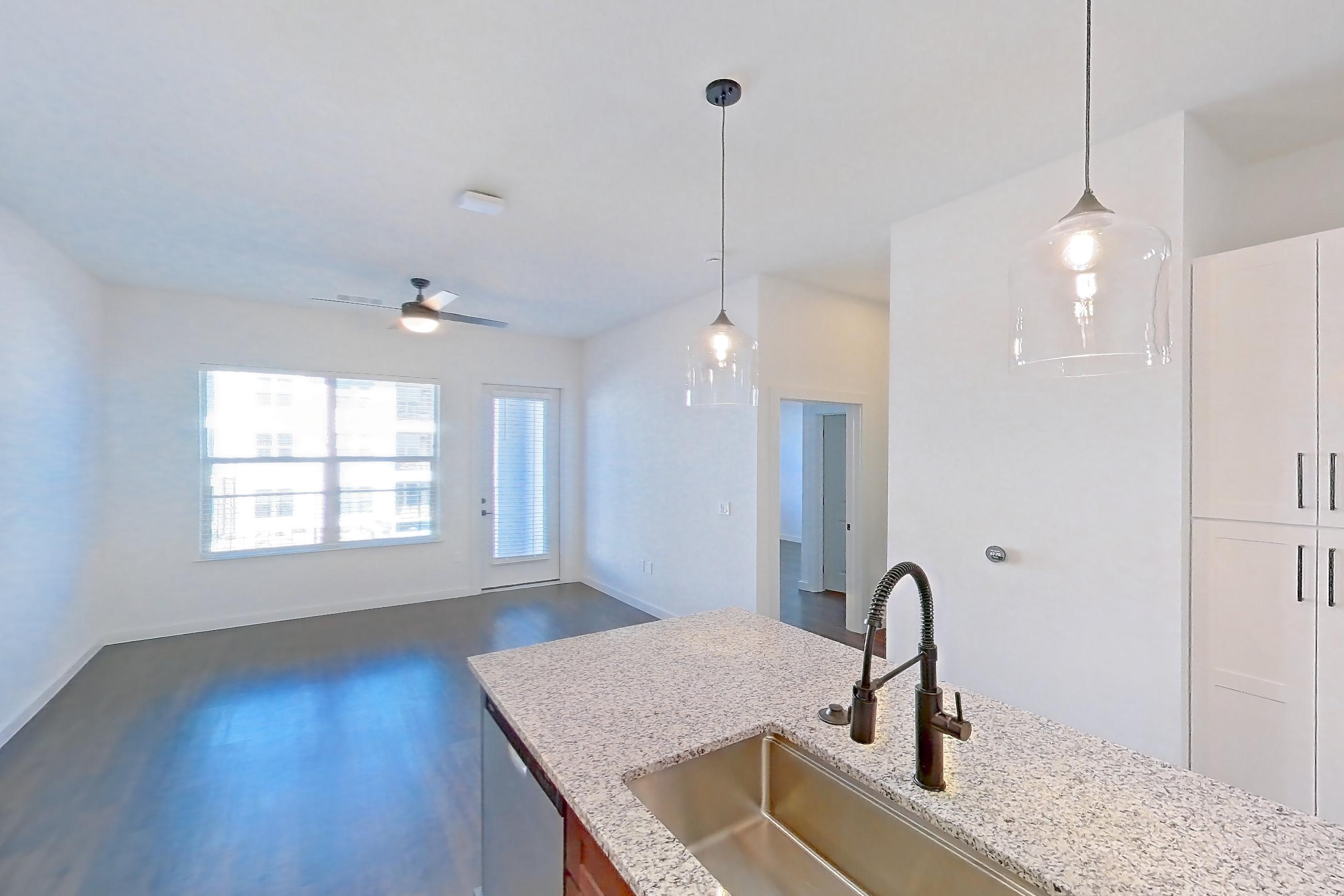 Kitchen with dark wood-finish flooring, dishwasher, electric range, light countertops, light stone countertops, oven/range, refrigerator, stainless steel appliances, water & ice dispenser, and white appliances, Apartment 1-214 at Cortland Peterson