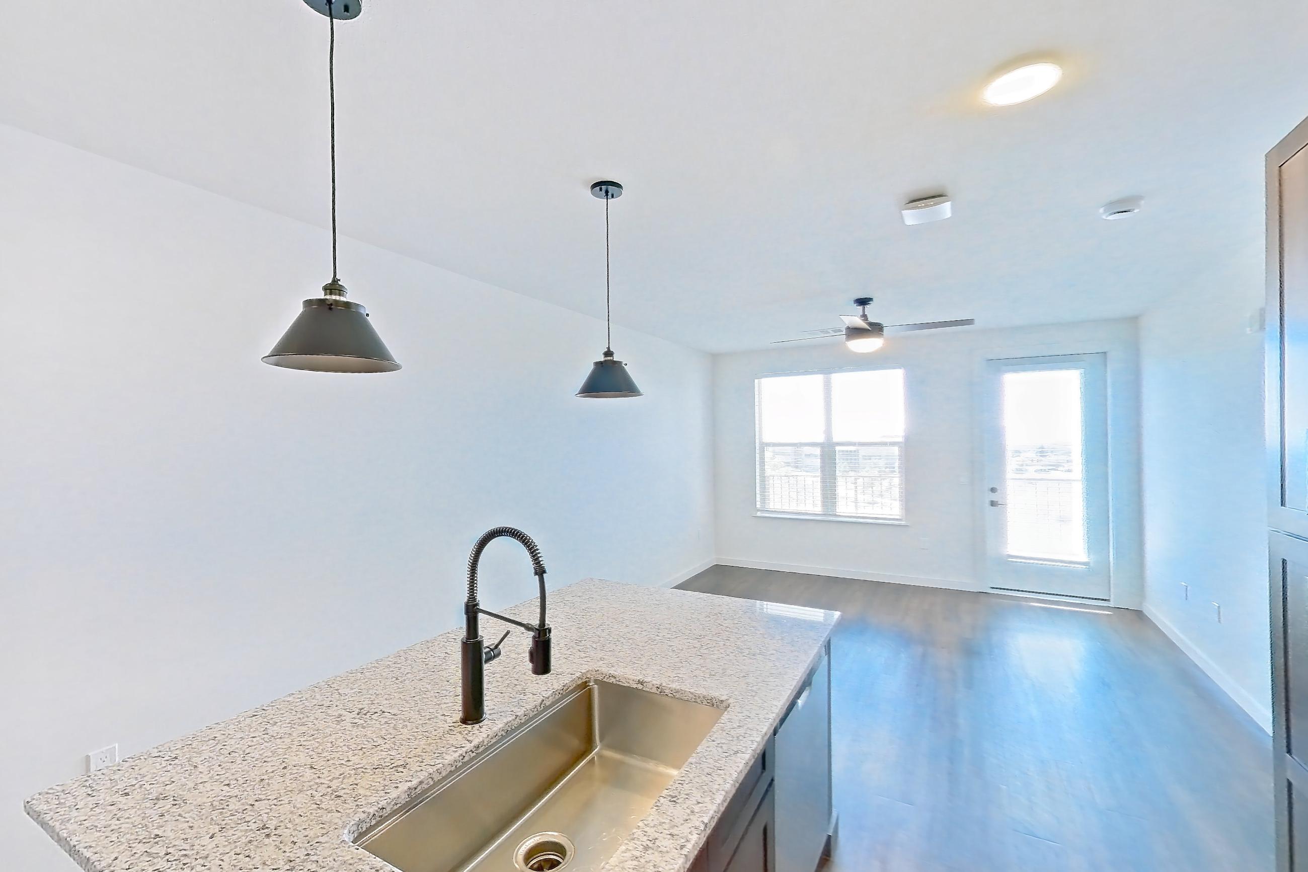 Kitchen with dark wood-finish flooring, dishwasher, electric range, light stone countertops, oven/range, refrigerator, stainless steel appliances, water & ice dispenser, and white appliances, Apartment 3-409 at Cortland Peterson