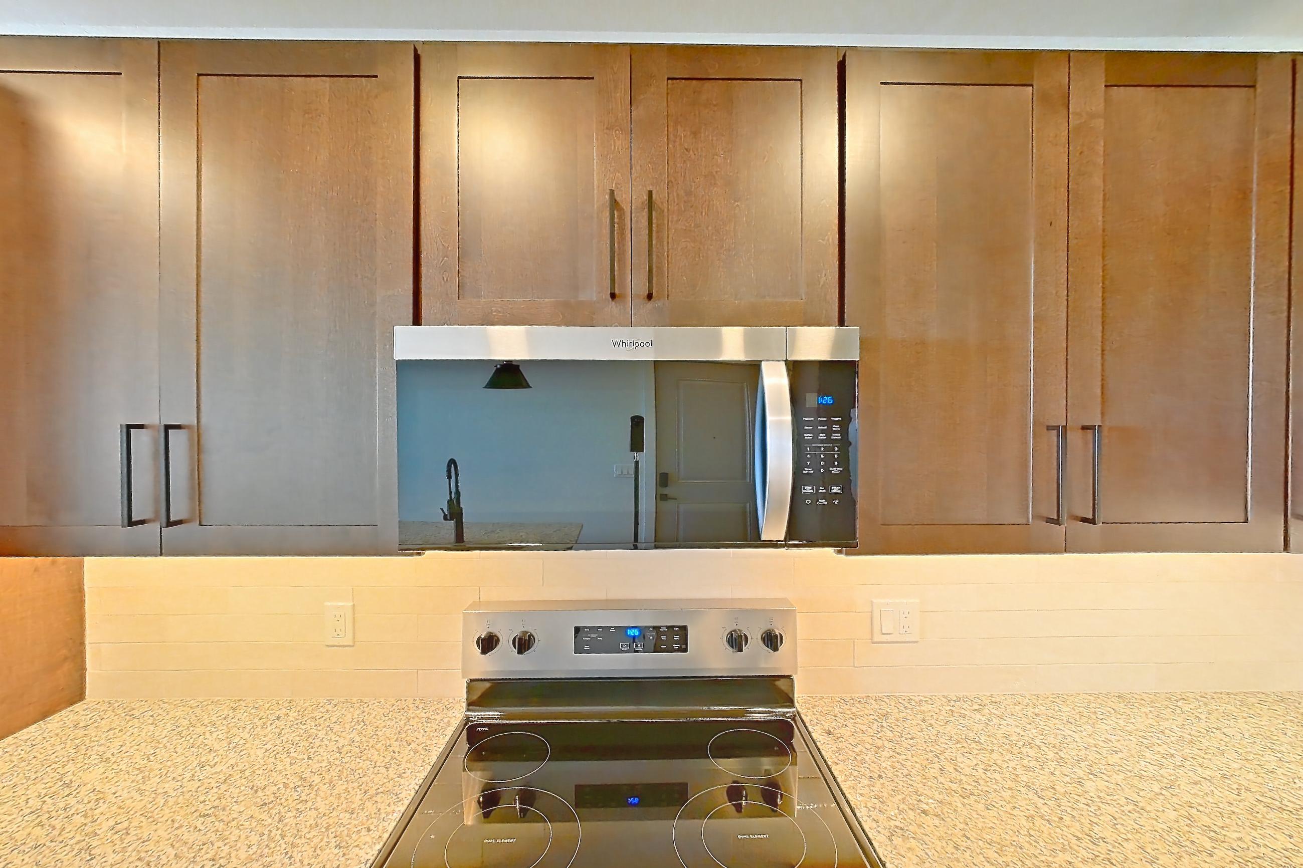 Kitchen with dark wood-finish flooring, dishwasher, electric range, light stone countertops, oven/range, refrigerator, stainless steel appliances, water & ice dispenser, and white appliances, Apartment 3-409 at Cortland Peterson