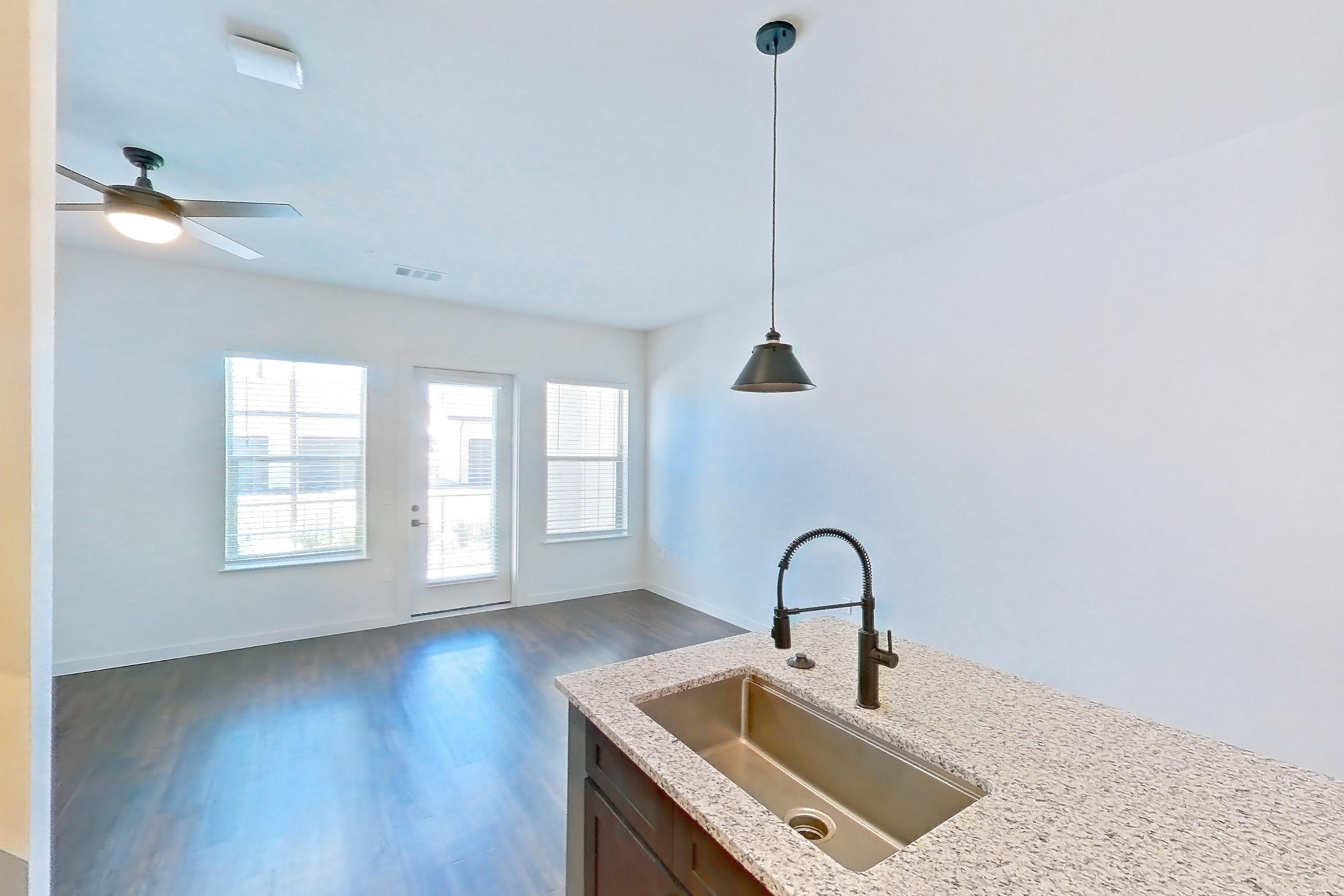 Kitchen with dark wood-finish flooring, dishwasher, electric range, light stone countertops, oven/range, refrigerator, stainless steel appliances, and water & ice dispenser, Apartment 1-116 at Cortland Peterson