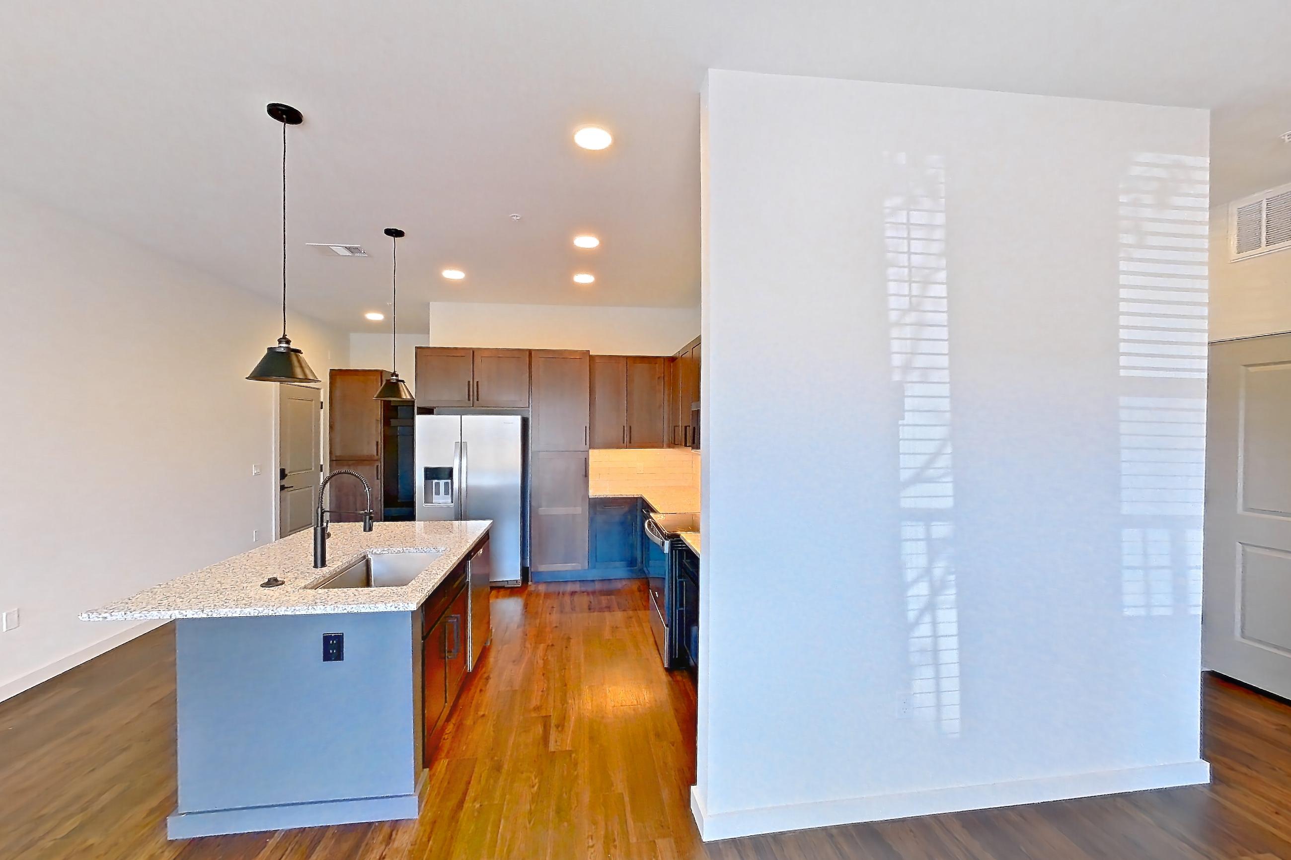 Living space with dark wood-finish flooring, electric range, kitchen island, light stone countertops, oven/range, refrigerator, stainless steel appliances, and water & ice dispenser, Apartment 1-116 at Cortland Peterson
