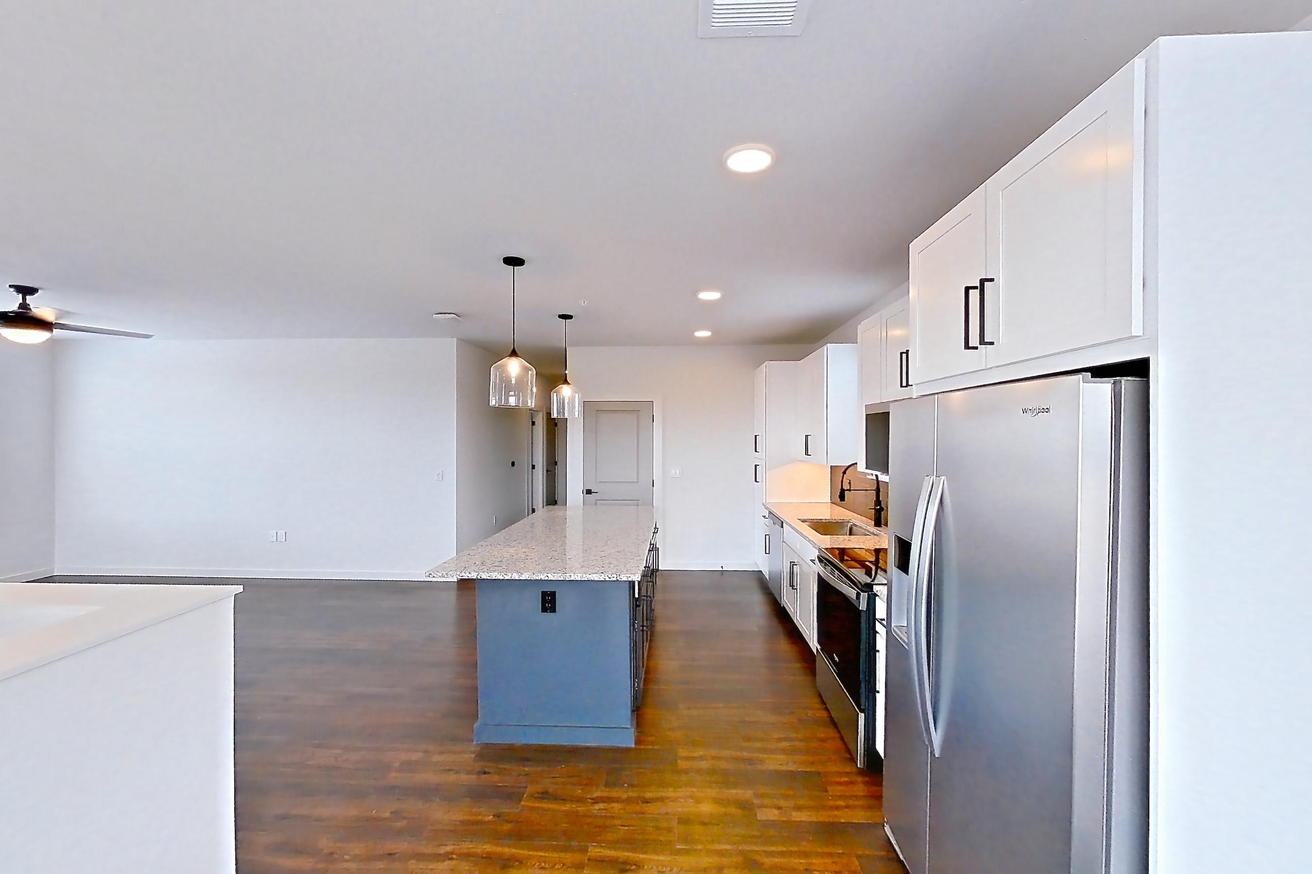 Dining room with dark wood-finish flooring, electric range, light stone countertops, oven/range, refrigerator, and stainless steel appliances, Apartment 6-202 at Cortland Peterson