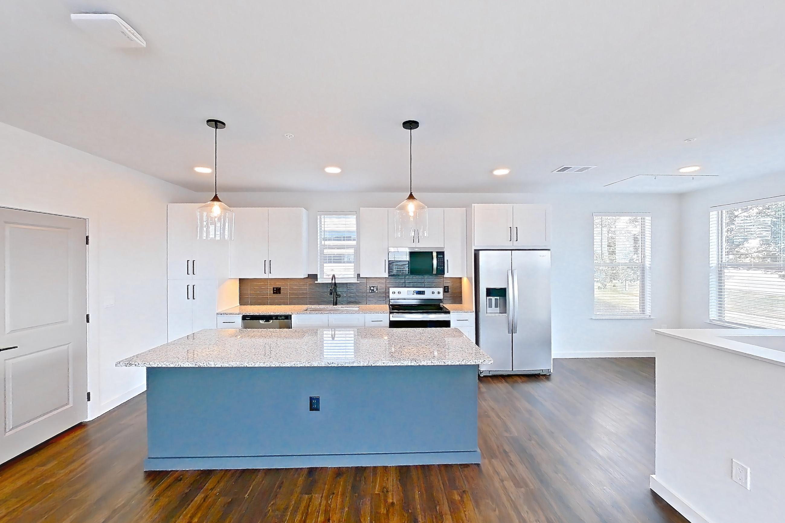 Living room with dark wood-finish flooring, dishwasher, electric range, light stone countertops, oven/range, refrigerator, stainless steel appliances, and water & ice dispenser, Apartment 6-202 at Cortland Peterson