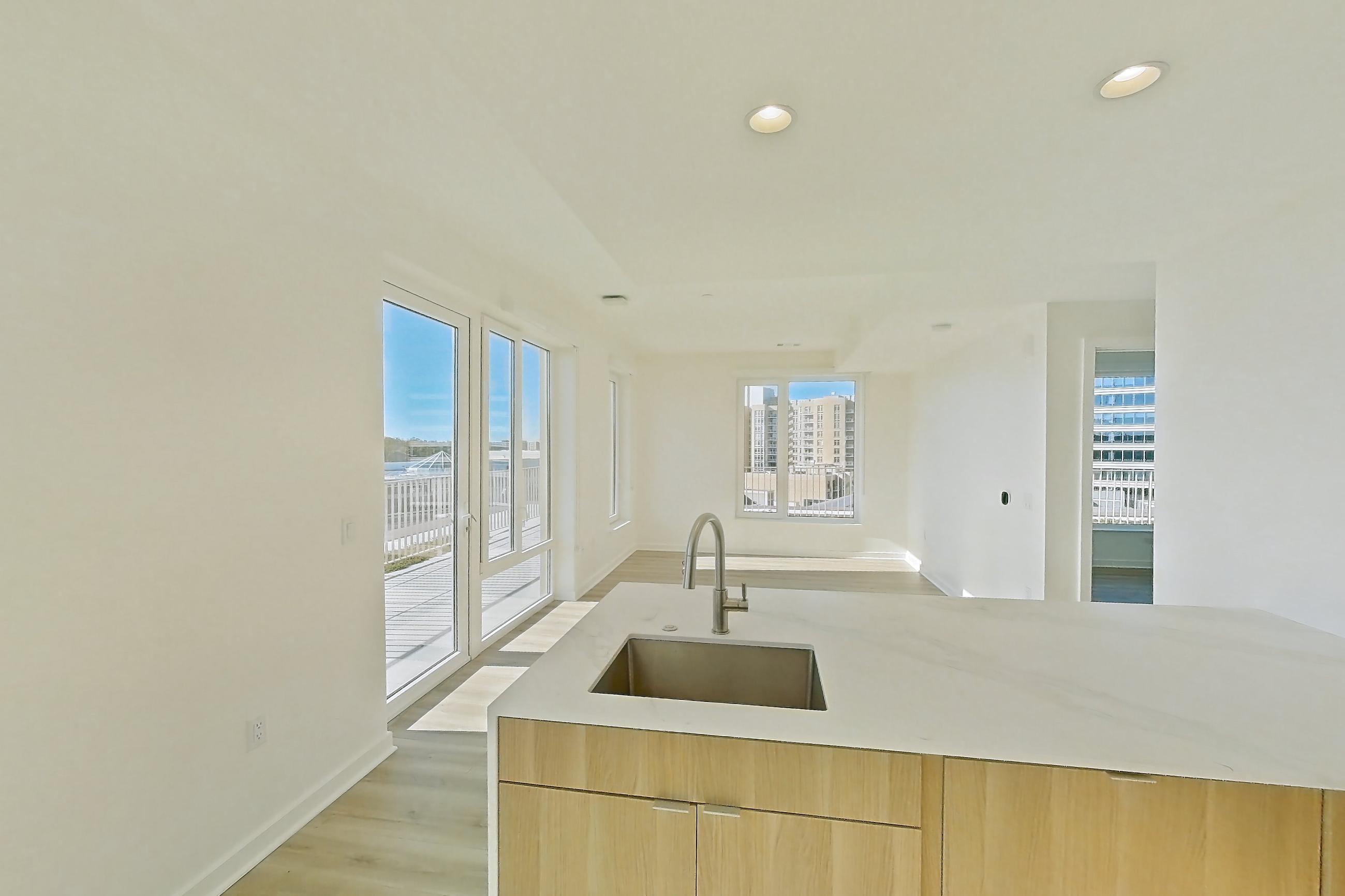 Kitchen with electric range, light stone countertops, light wood-finish flooring, oven/range, and stainless steel appliances, Apartment PH11 at Residences at Mazza