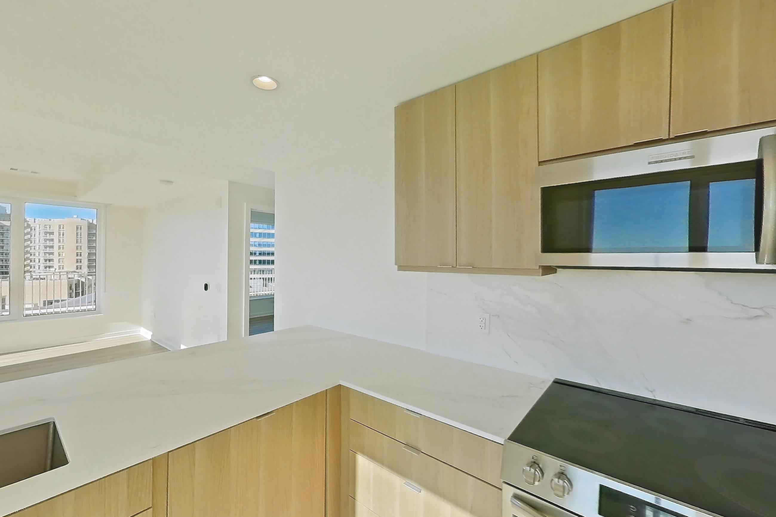 Kitchen with electric range, light stone countertops, light wood-finish flooring, oven/range, and stainless steel appliances, Apartment PH11 at Residences at Mazza