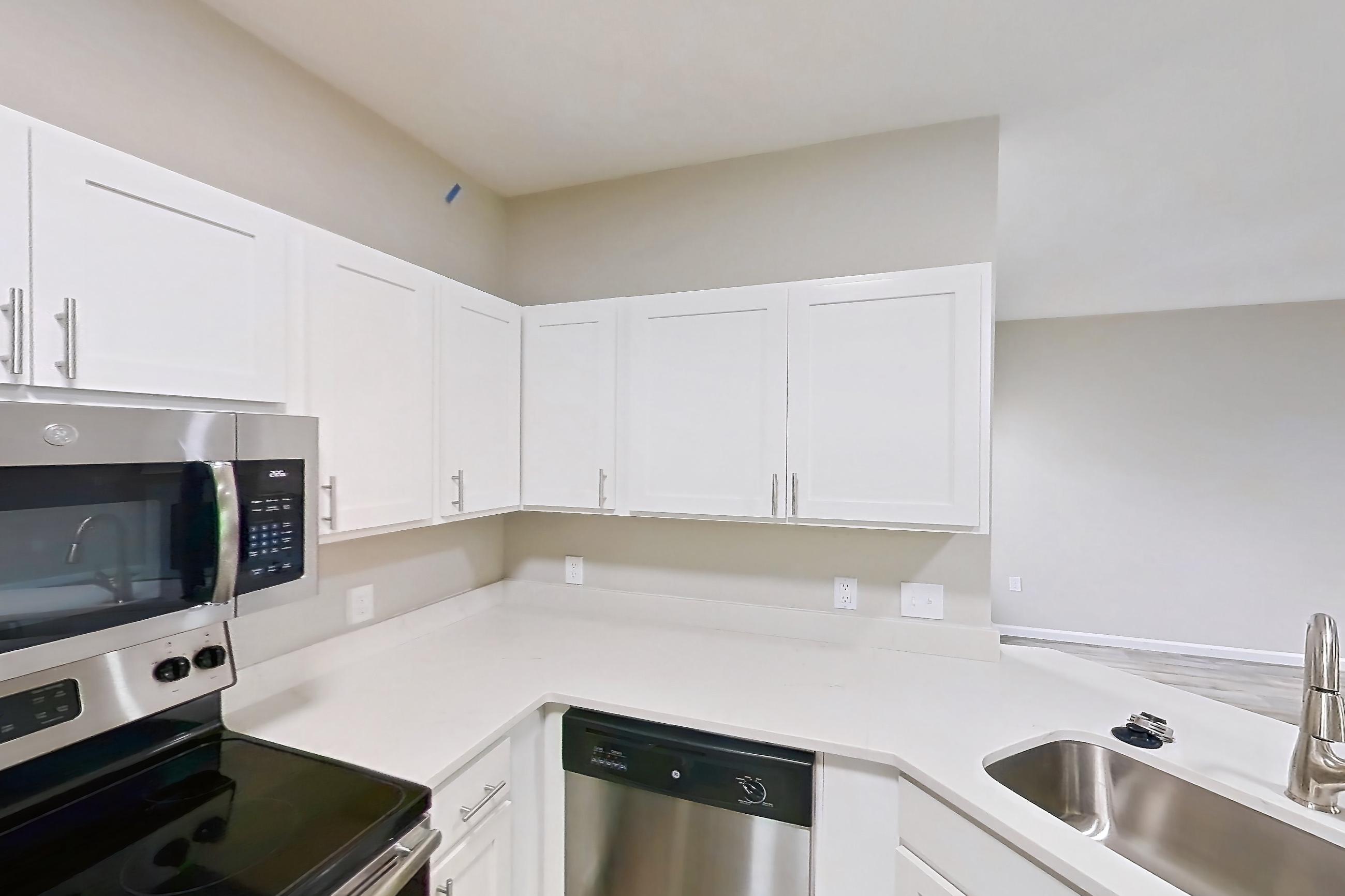 Kitchen with dishwasher, electric range, fireplace, light stone countertops, light wood-finish flooring, microwave, oven/range, and stainless steel appliances, Apartment Bradford 1 at Bradford Pointe