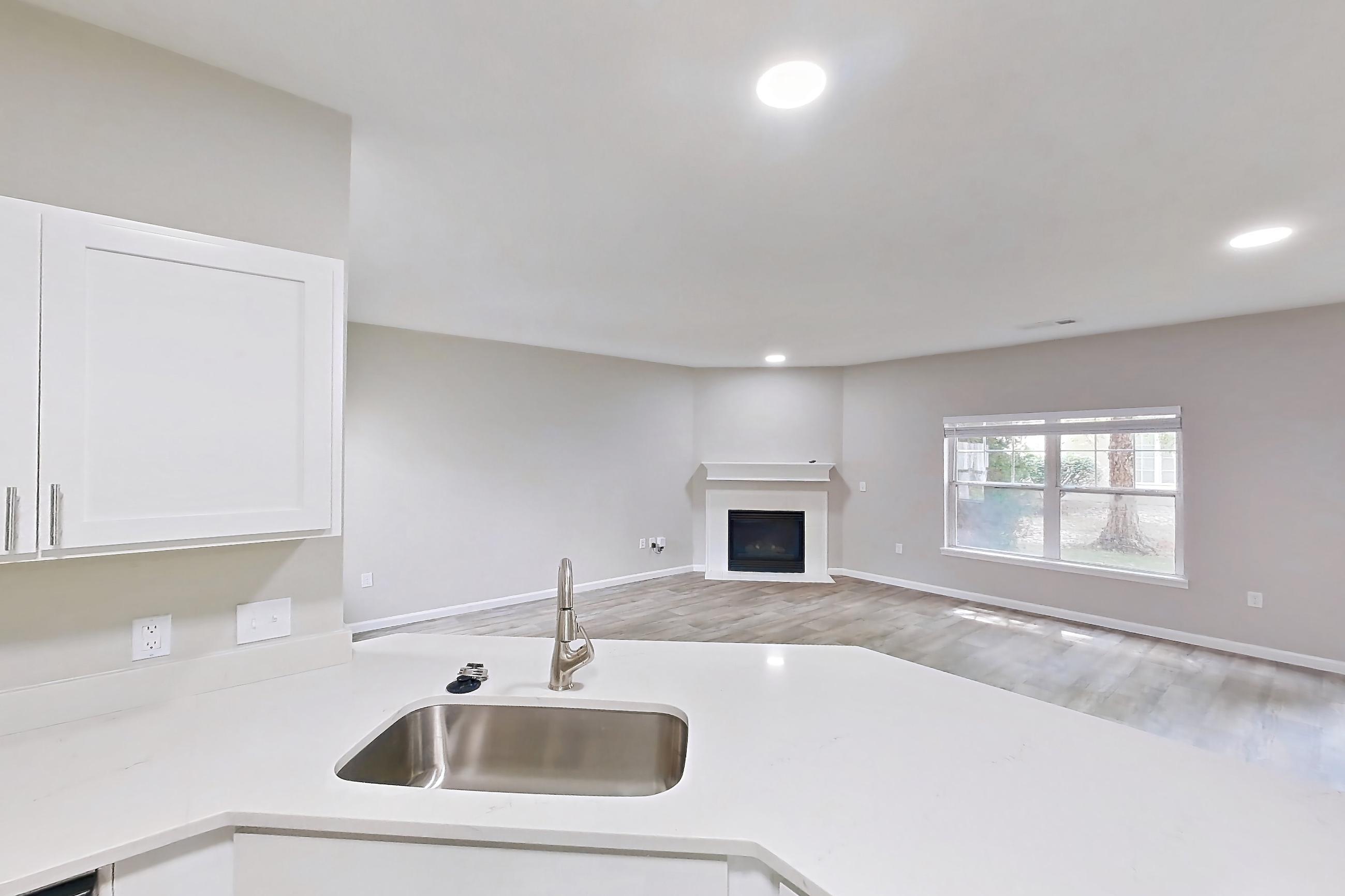 Kitchen with dishwasher, electric range, fireplace, light stone countertops, light wood-finish flooring, microwave, oven/range, and stainless steel appliances, Apartment Bradford 1 at Bradford Pointe