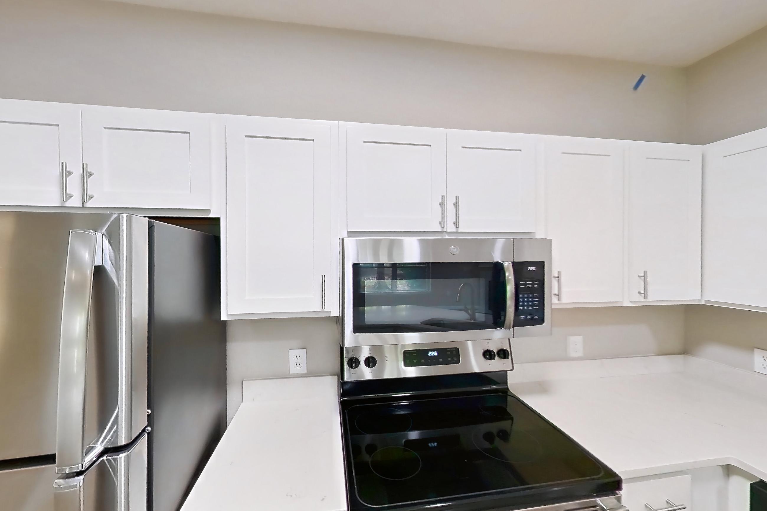 Kitchen with dishwasher, electric range, fireplace, light stone countertops, light wood-finish flooring, microwave, oven/range, and stainless steel appliances, Apartment Bradford 1 at Bradford Pointe