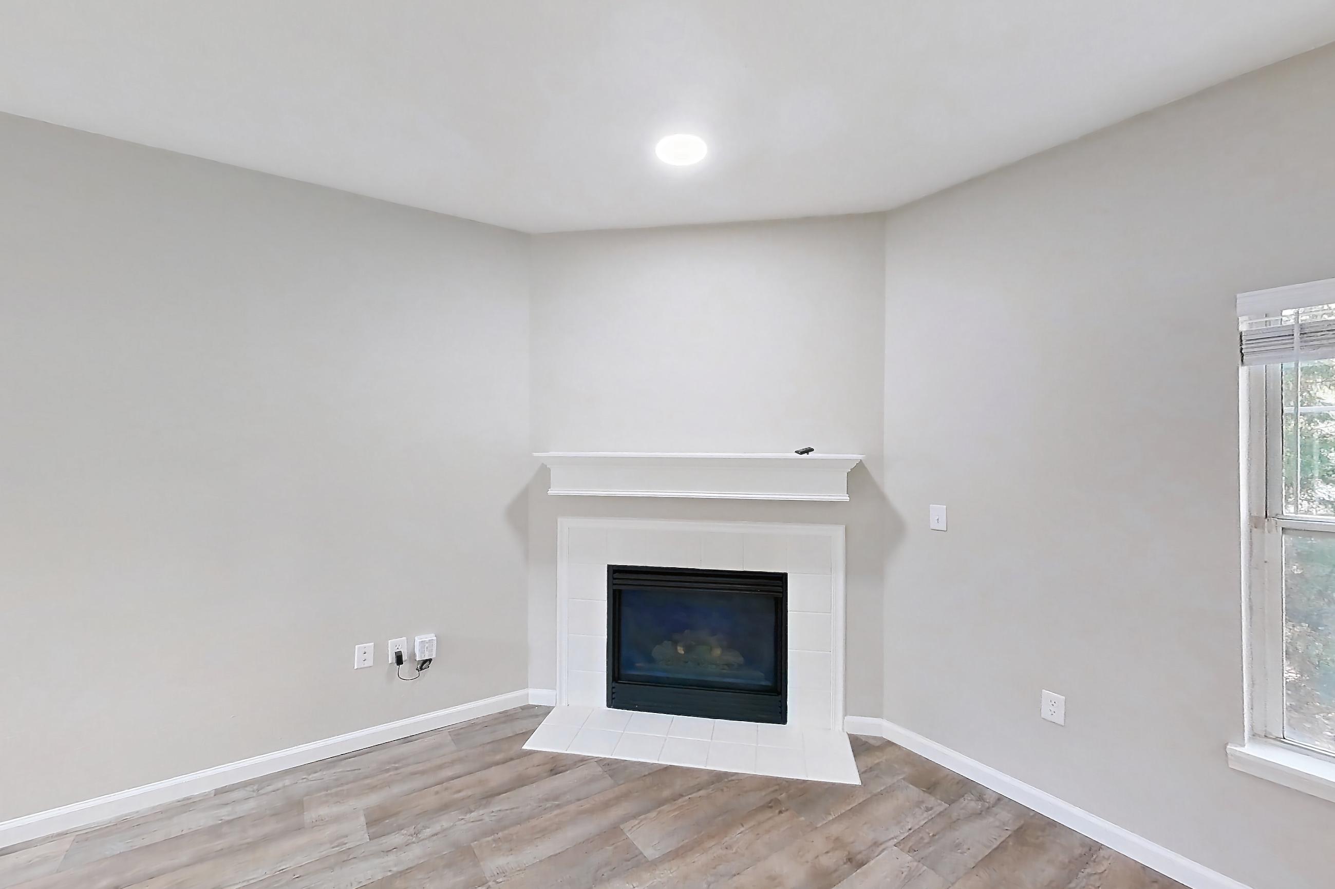 Living room with fireplace, light wood-finish flooring, and tile fireplace, Apartment Bradford 1 at Bradford Pointe