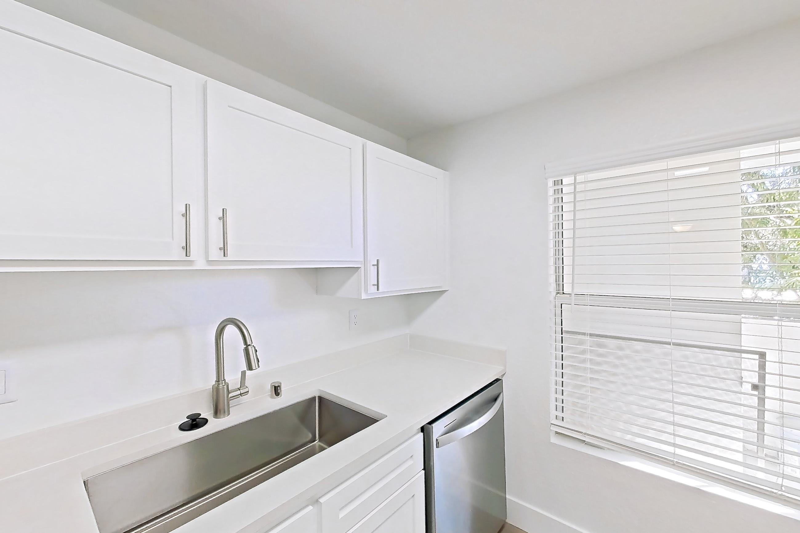 Kitchen with dishwasher, electric range, light countertops, light wood-finish flooring, microwave, oven/range, refrigerator, and stainless steel appliances, Apartment 01-2004 at Xander 3900