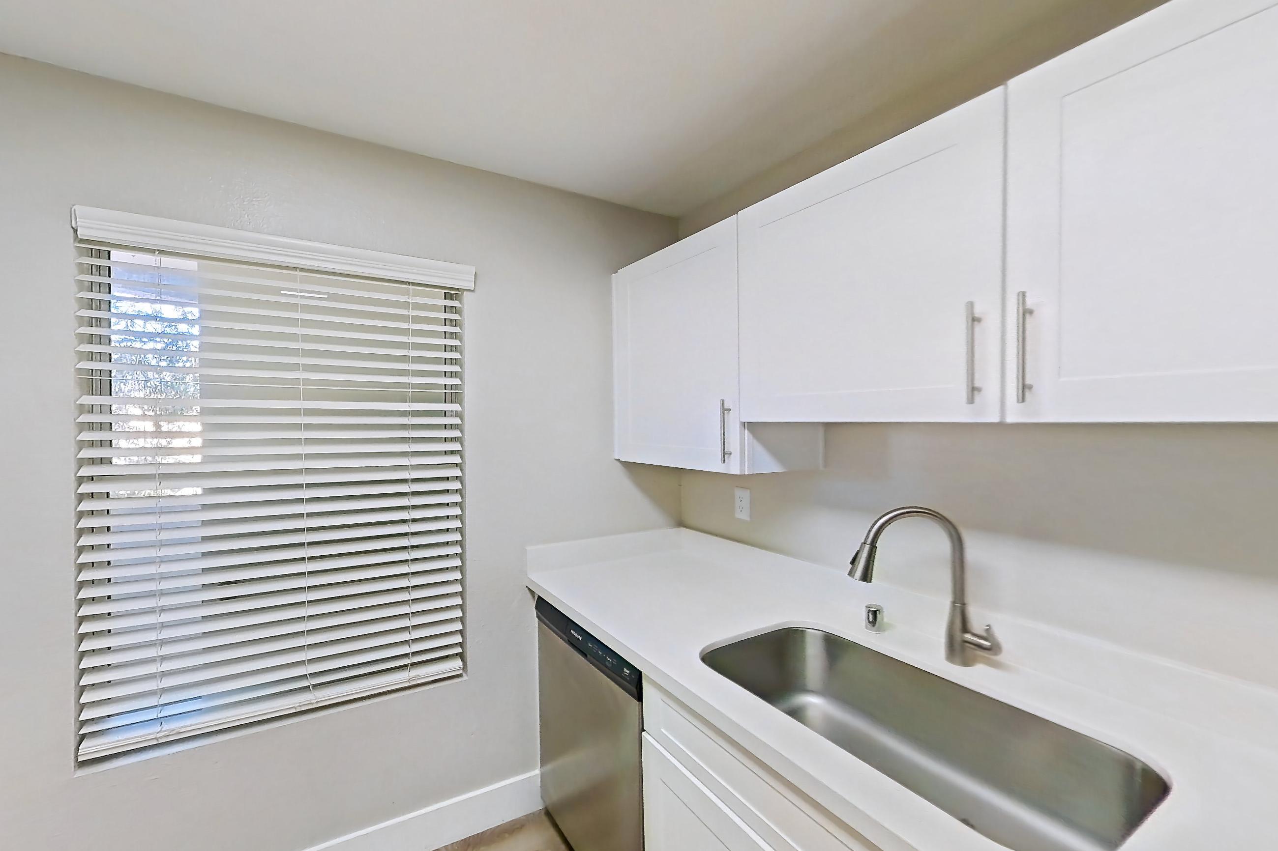 Kitchen with dishwasher, electric range, light countertops, light wood-finish flooring, microwave, oven/range, and stainless steel appliances, Apartment 14-2107 at Xander 3900