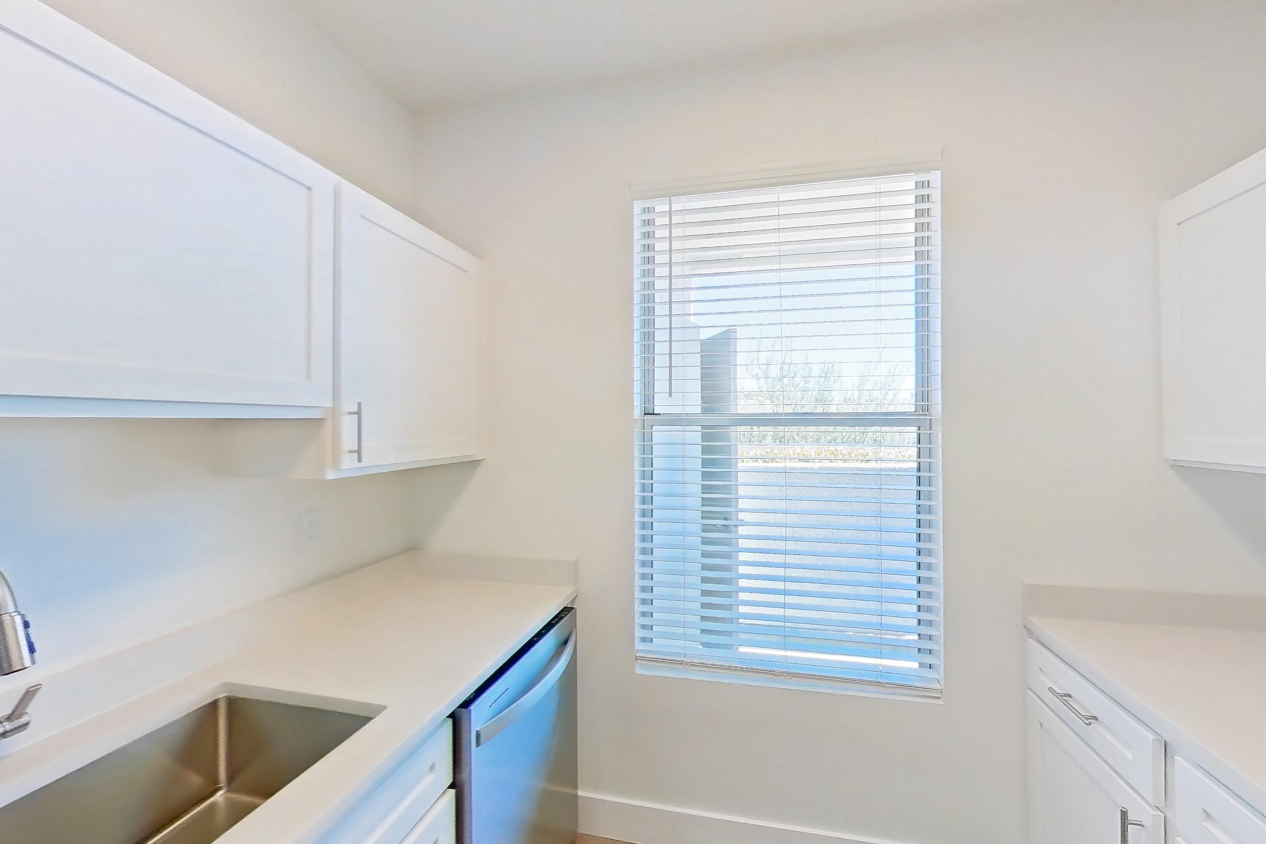 Kitchen with dishwasher, electric range, light countertops, light stone countertops, light wood-finish flooring, microwave, oven/range, and stainless steel appliances, Apartment 18-1050 at Xander 3900