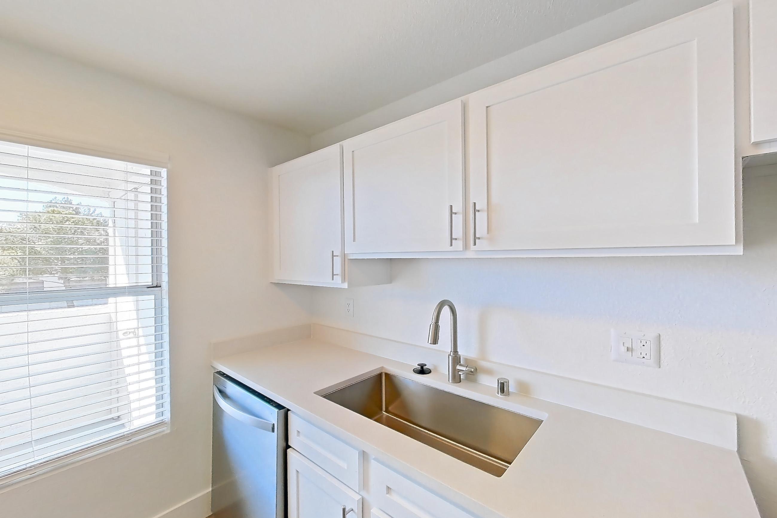 Kitchen with dishwasher, electric range, light countertops, light stone countertops, light wood-finish flooring, microwave, oven/range, refrigerator, and stainless steel appliances, Apartment 34-2089 at Xander 3900