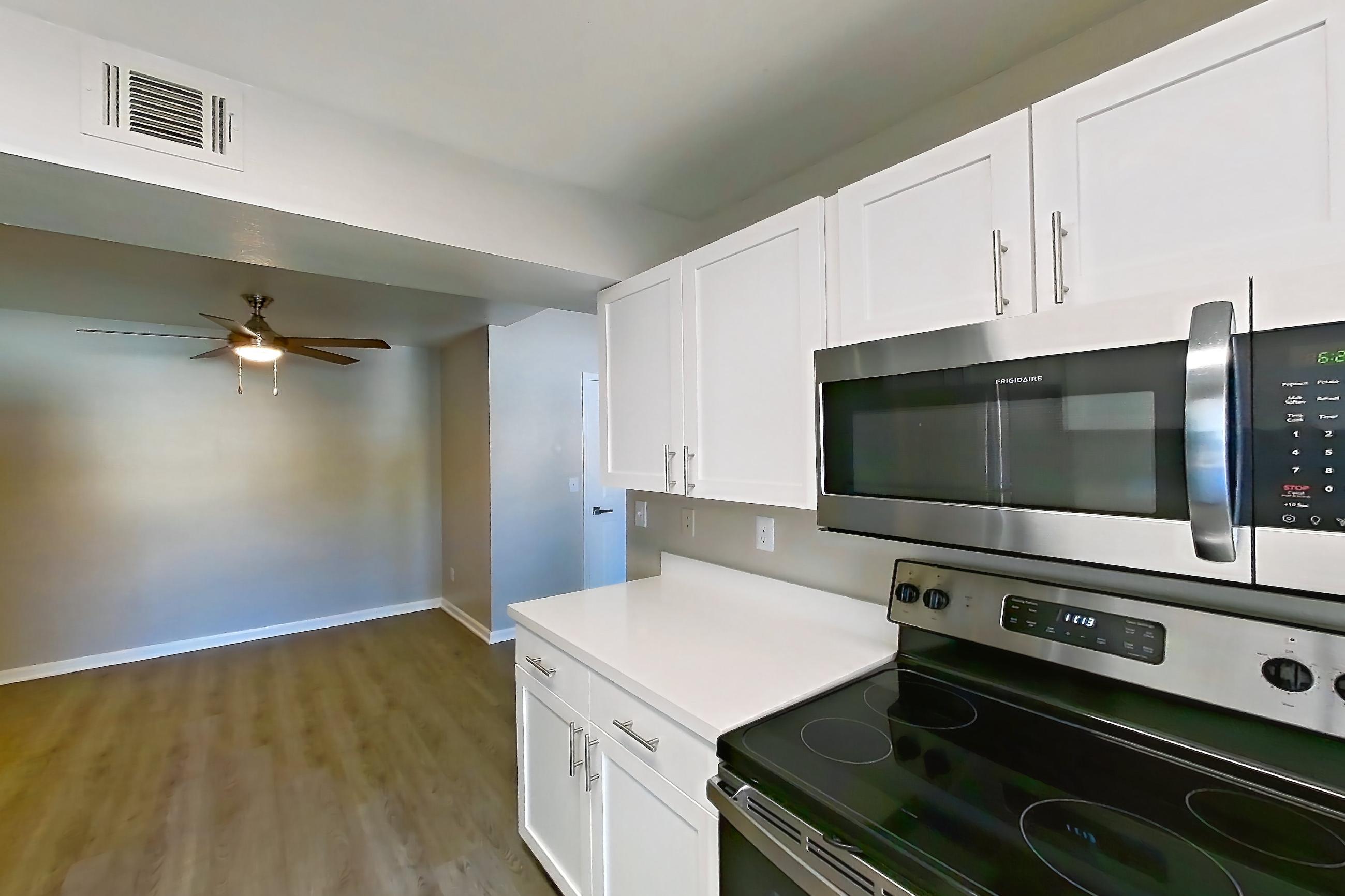 Kitchen with electric range, light countertops, light wood-finish flooring, microwave, oven/range, refrigerator, and stainless steel appliances, Apartment 19-2039 at Xander 3900