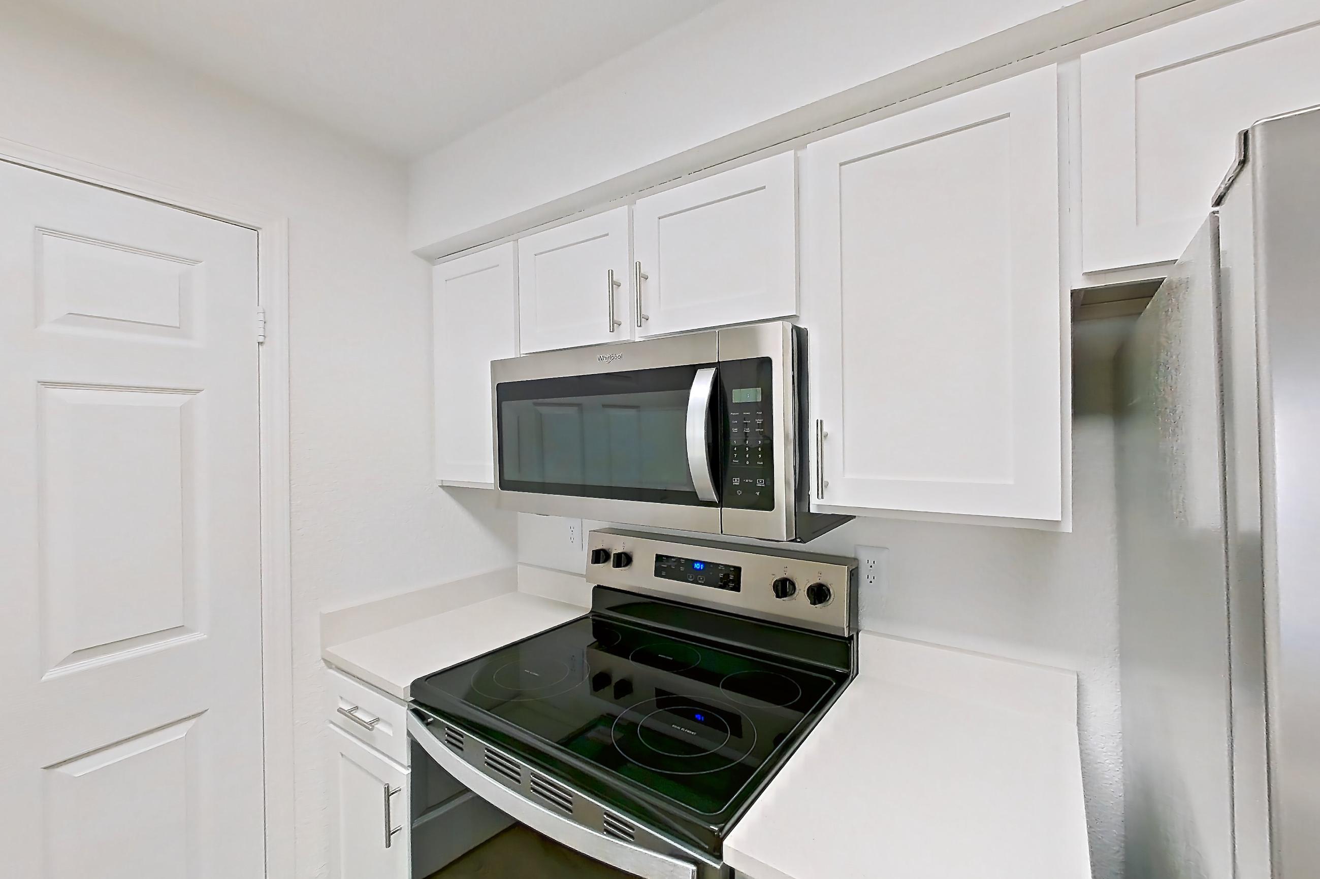 Kitchen with dishwasher, electric range, light countertops, light wood-finish flooring, microwave, oven/range, refrigerator, and stainless steel appliances, Apartment 30-2083 at Xander 3900
