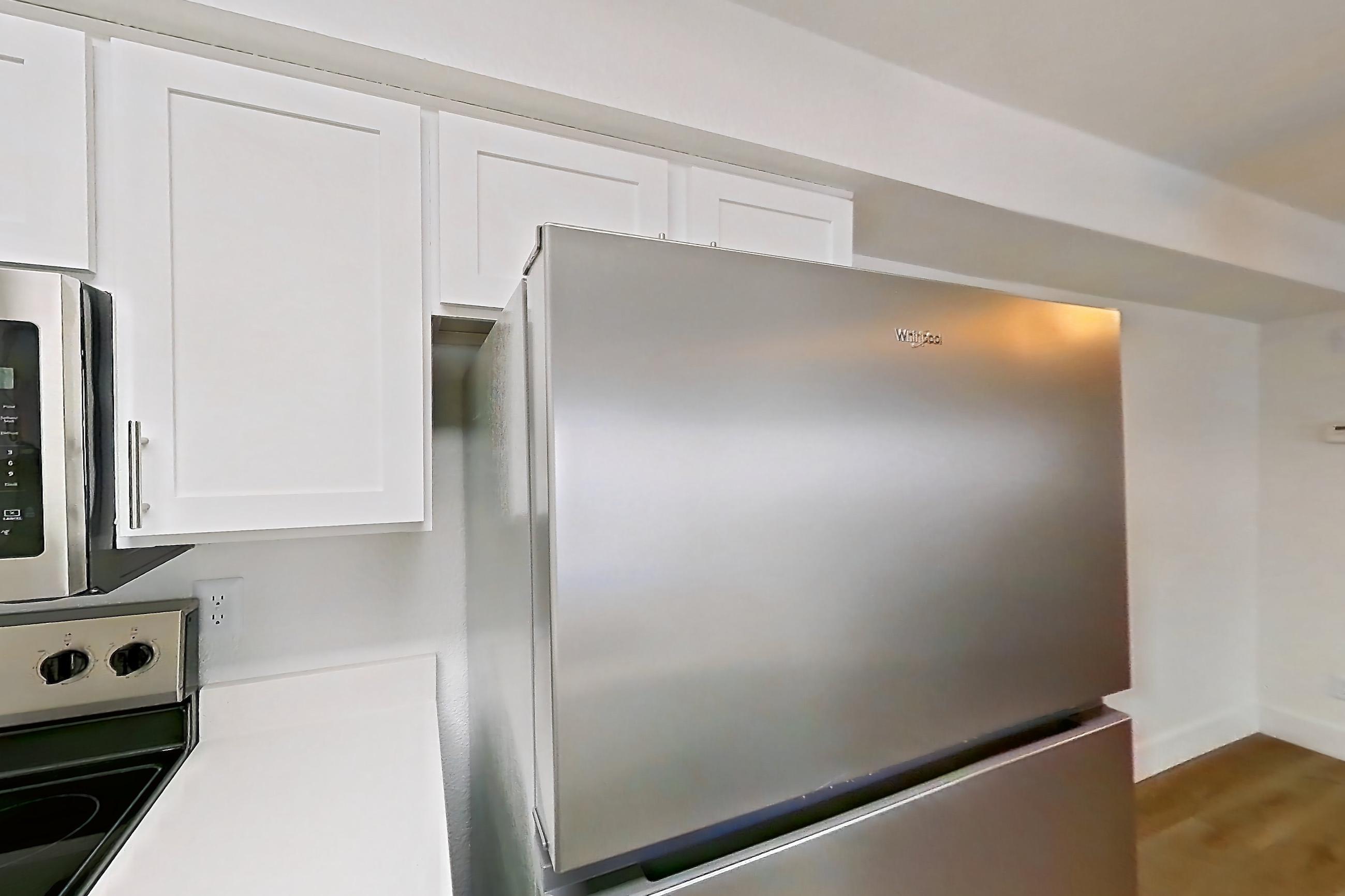 Kitchen with dishwasher, electric range, light countertops, light wood-finish flooring, microwave, oven/range, refrigerator, and stainless steel appliances, Apartment 30-2083 at Xander 3900