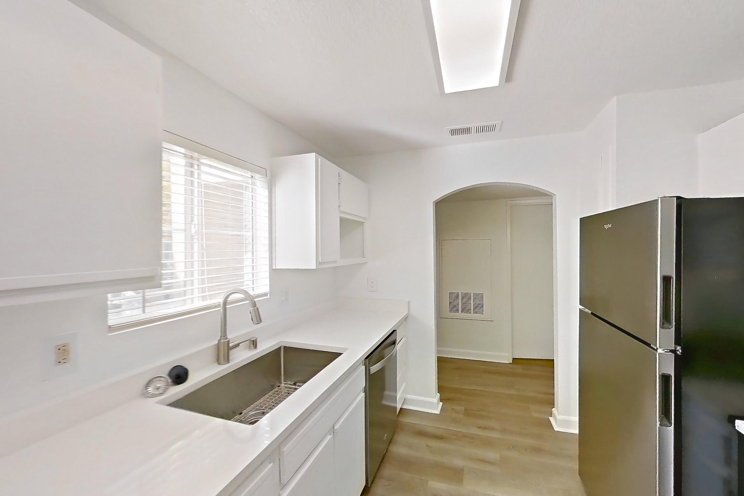 Kitchen with dishwasher, gas cooktop, gas range, light countertops, light wood-finish flooring, microwave, oven/range, refrigerator, and stainless steel appliances, Apartment 2110 at Vintage Pointe