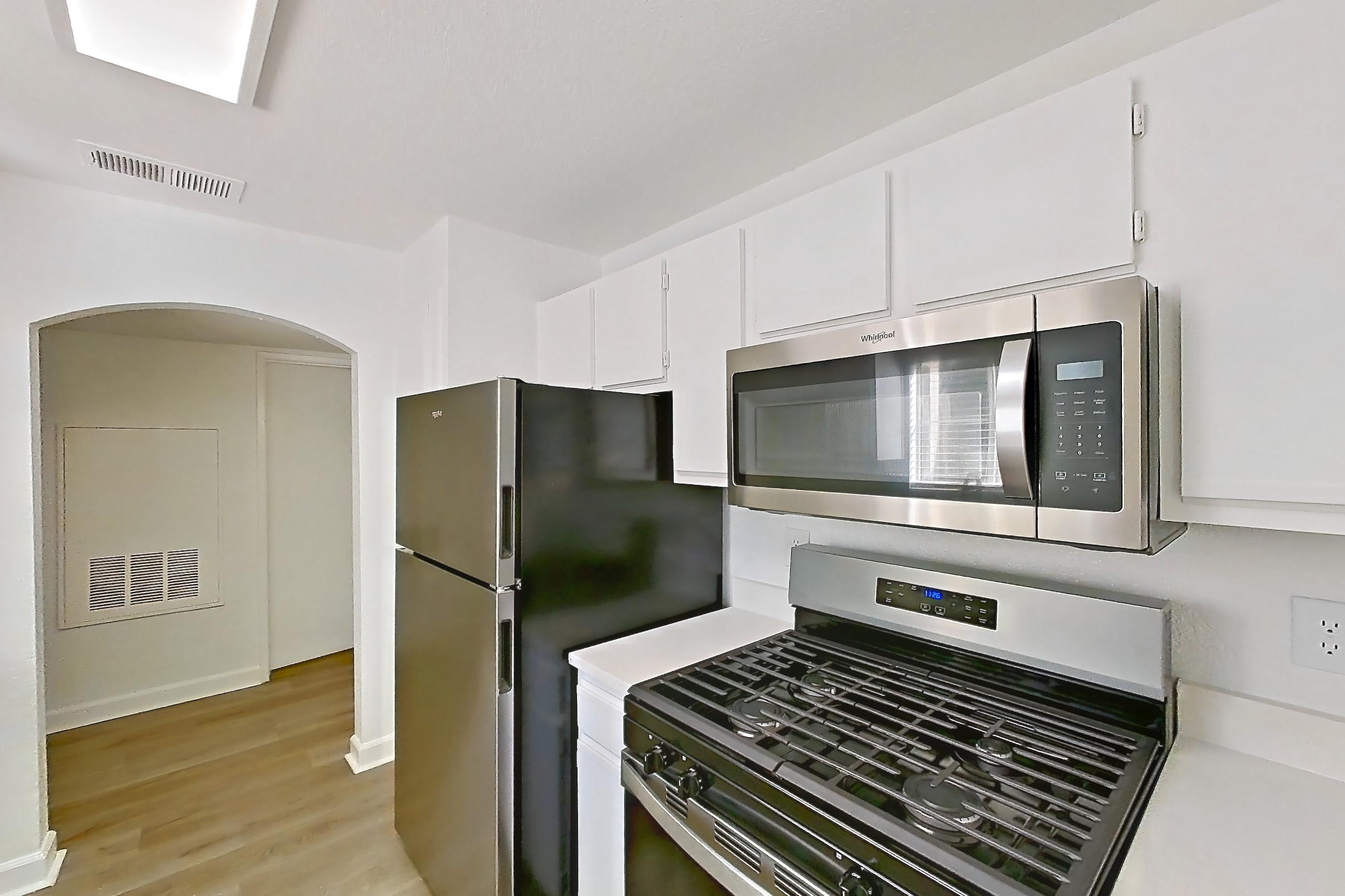 Kitchen with dishwasher, gas cooktop, gas range, light countertops, light wood-finish flooring, microwave, oven/range, refrigerator, and stainless steel appliances, Apartment 2110 at Vintage Pointe