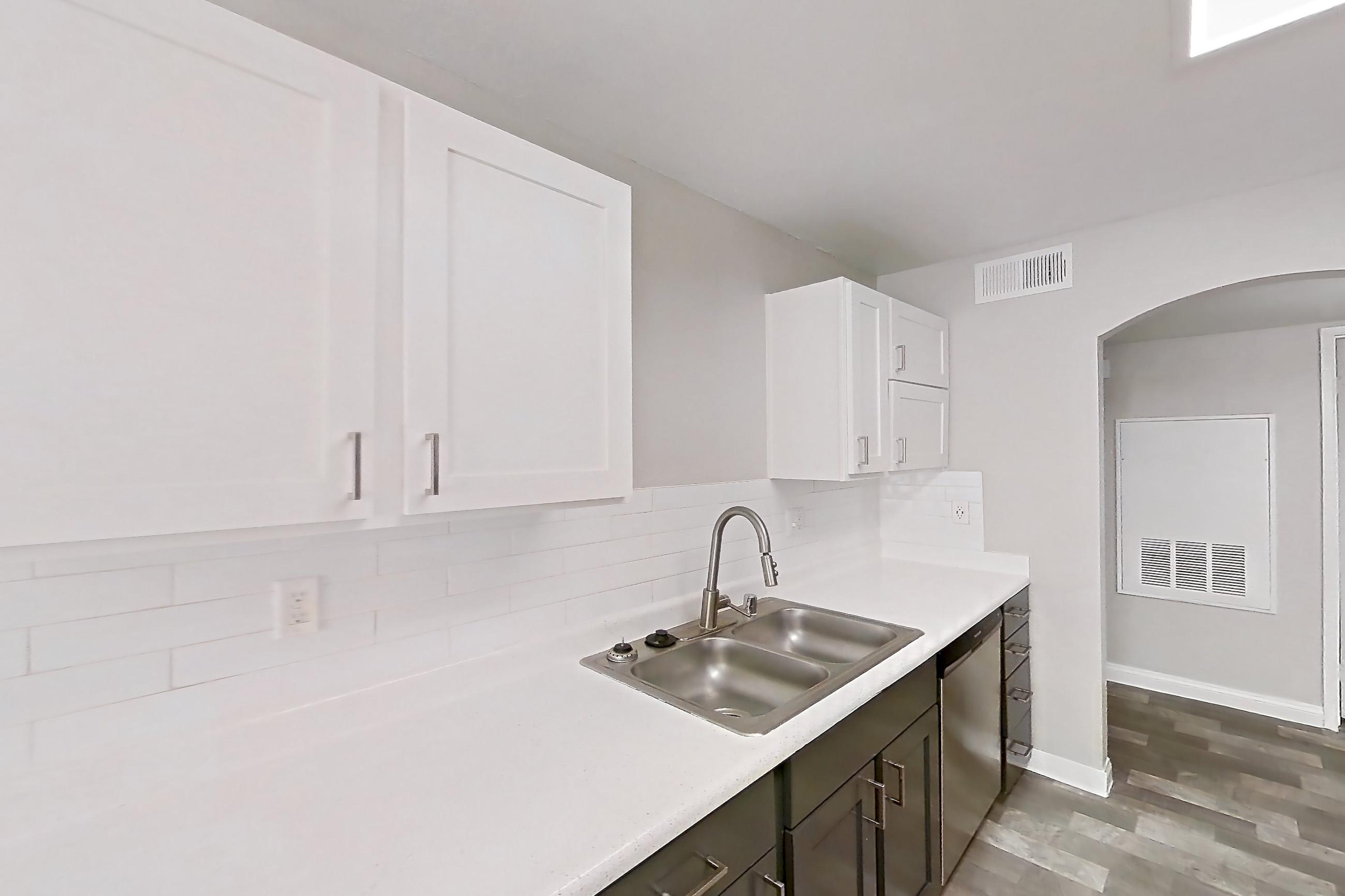 Kitchen with gas range, in-unit laundry, light countertops, light wood-finish flooring, microwave, oven/range, refrigerator, and stainless steel appliances, Apartment 1018 at Vintage Pointe