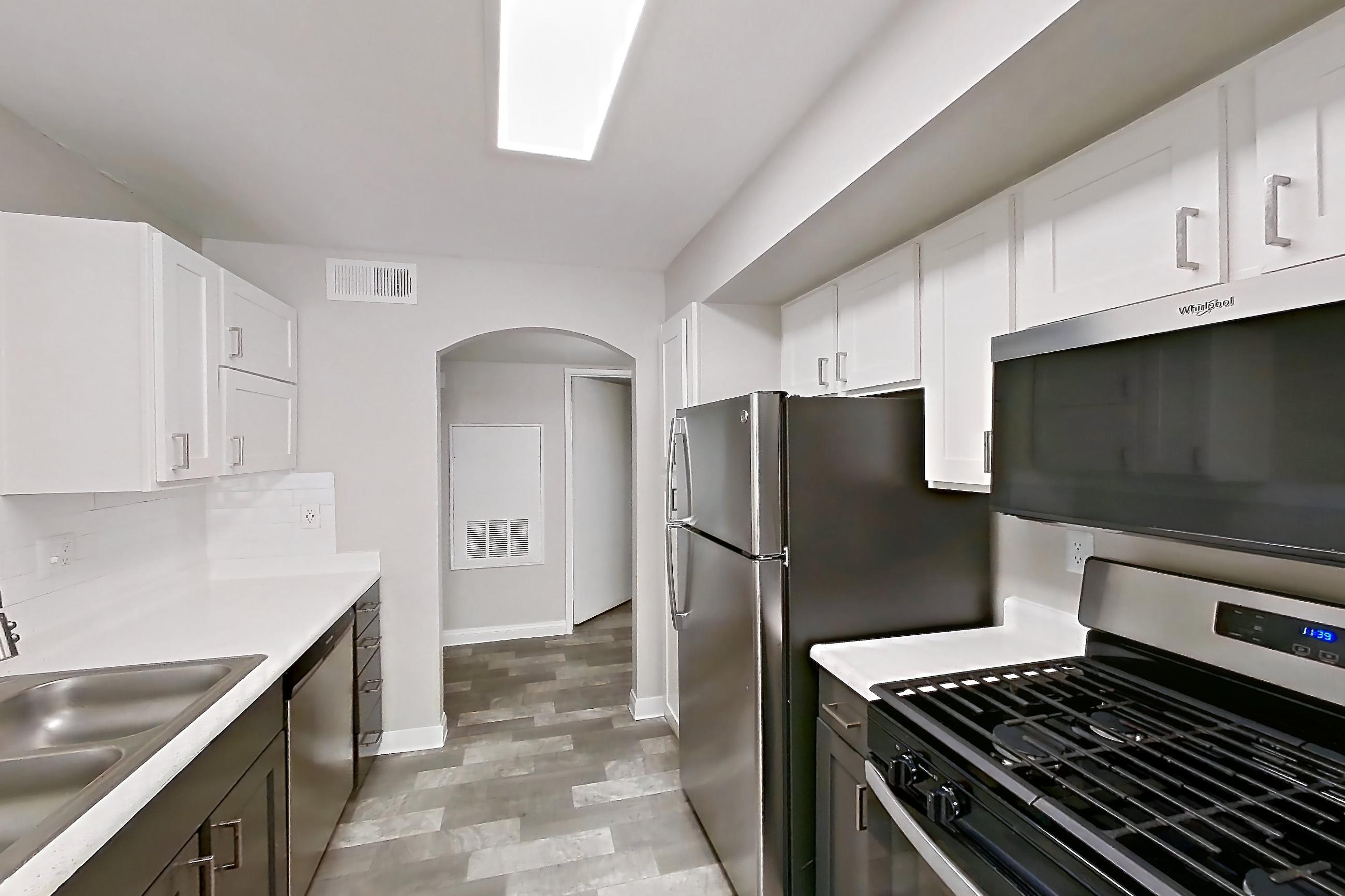 Kitchen with gas range, in-unit laundry, light countertops, light wood-finish flooring, microwave, oven/range, refrigerator, and stainless steel appliances, Apartment 1018 at Vintage Pointe